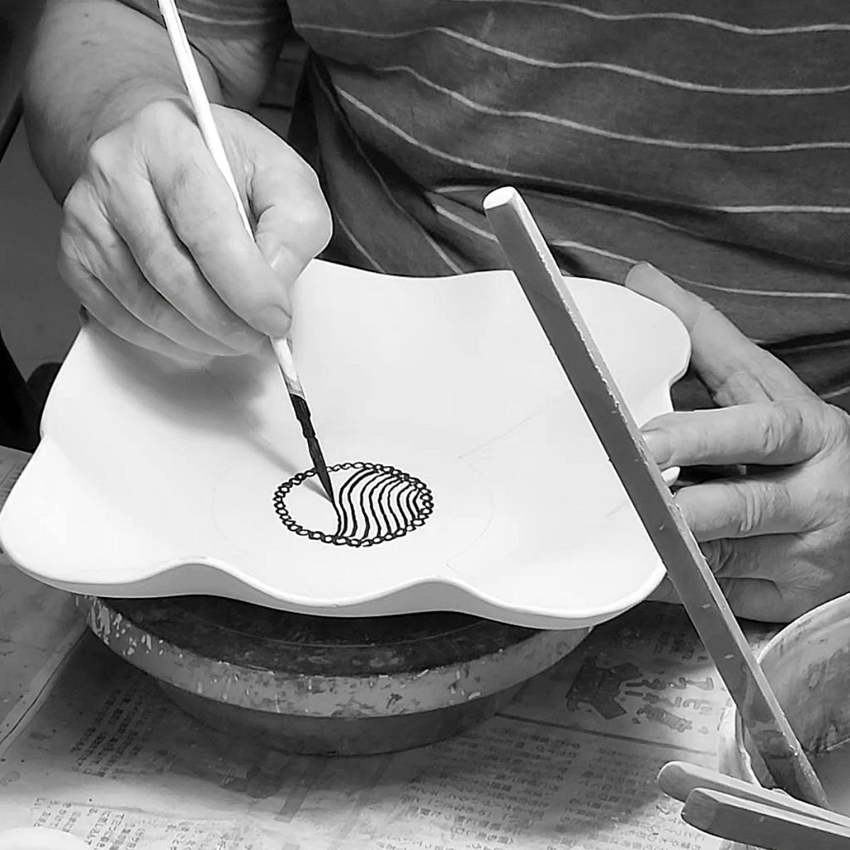 Hand painting a pottery plate in Japan. Tsukushi