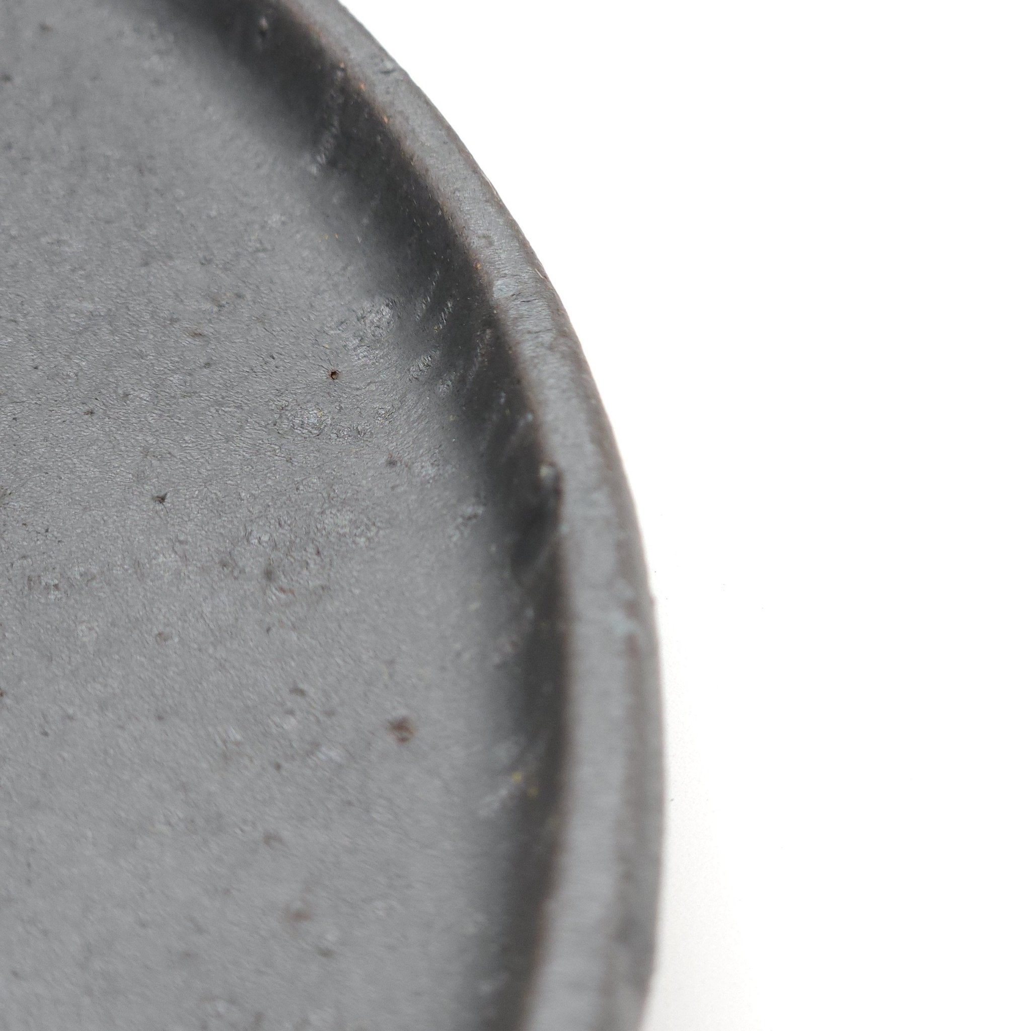 Side detail of a black Japanese pottery round Plate 24cm (9.4")