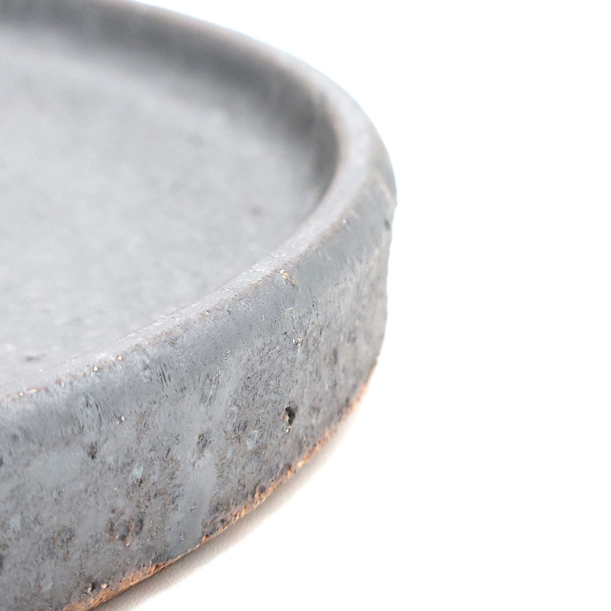 Side detail of a black Japanese pottery round Plate 24cm (9.4"). view 2