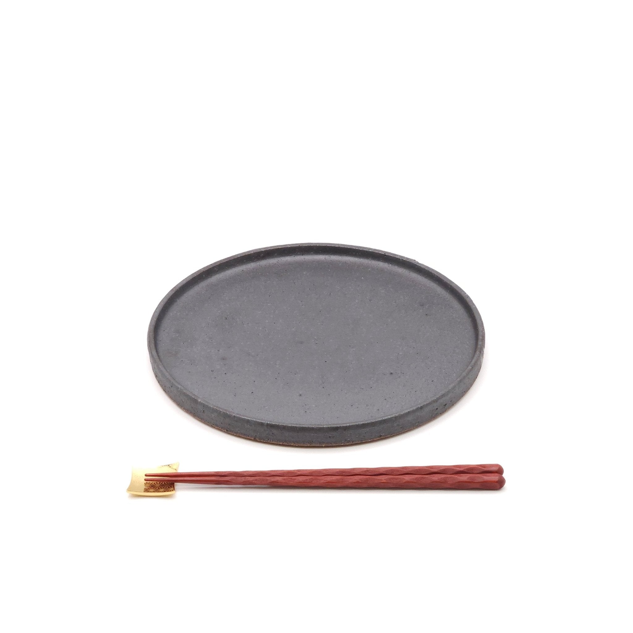 Front view of a black Japanese pottery round Plate 24cm (9.4") with chopsticks.