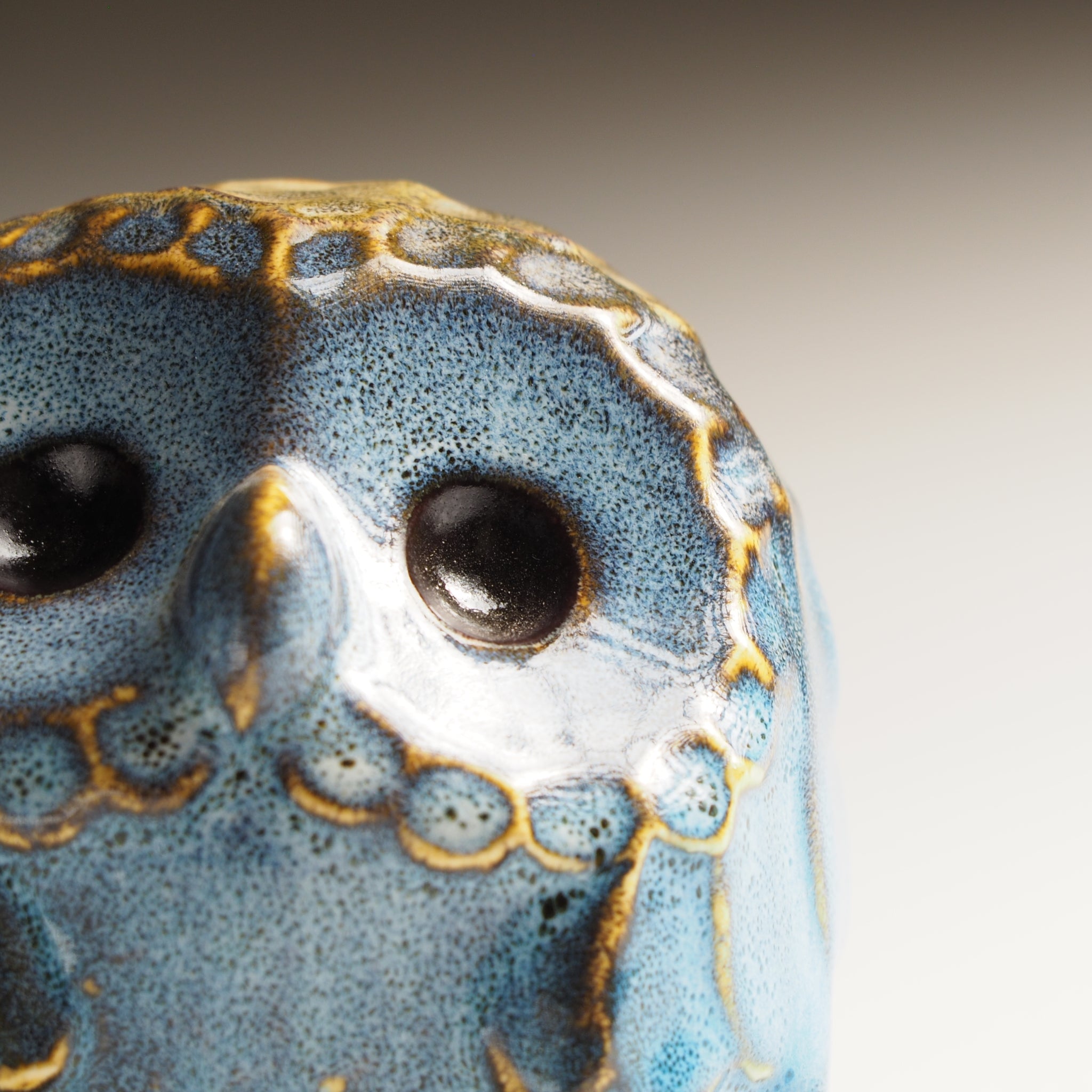 Close-up of the small Fukumori ceramic owl figurine with blue and gold glaze.