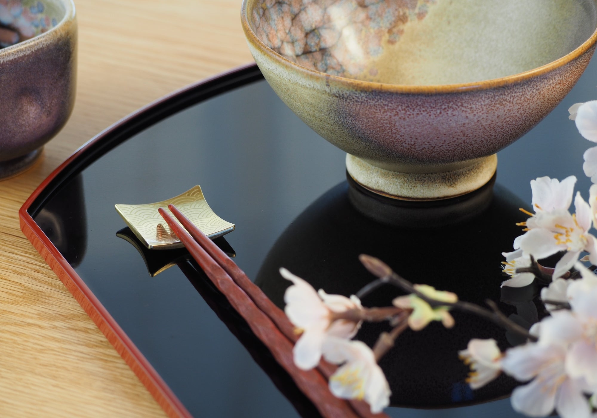 Black lacquer tray with Japanese chopsticks and Japanese rice bowl on a wooden table. Tsukushi