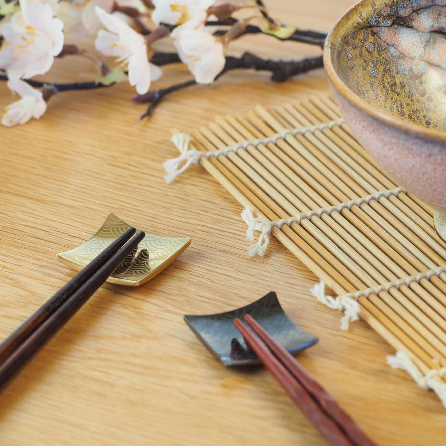 Two Japanese Chopsticks and two chopstick rests on a wooden surface with a bamboo mat. Tsukushi