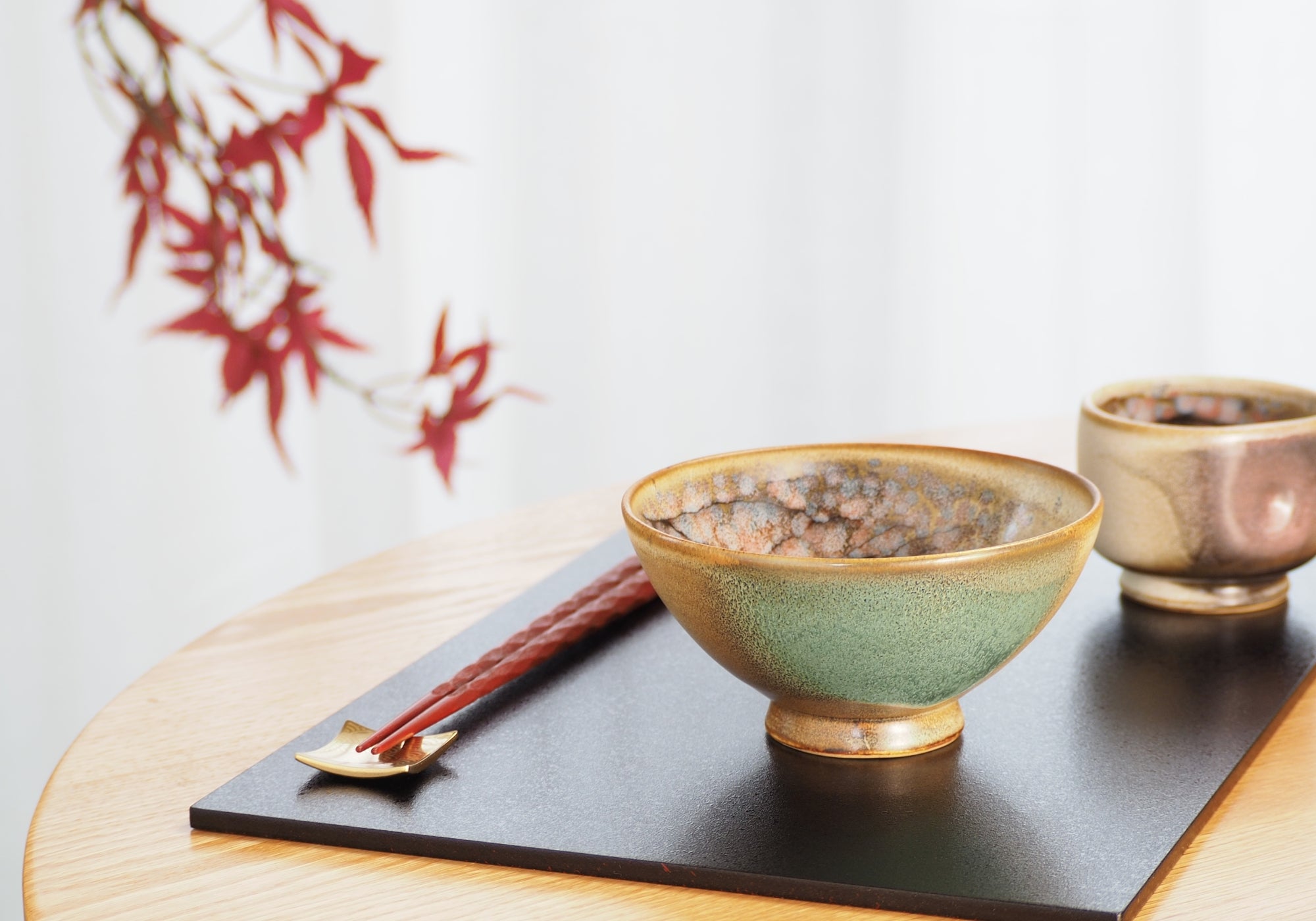 A Japanese ceramic bowl and teacup placed on a black tray. Tsukushi