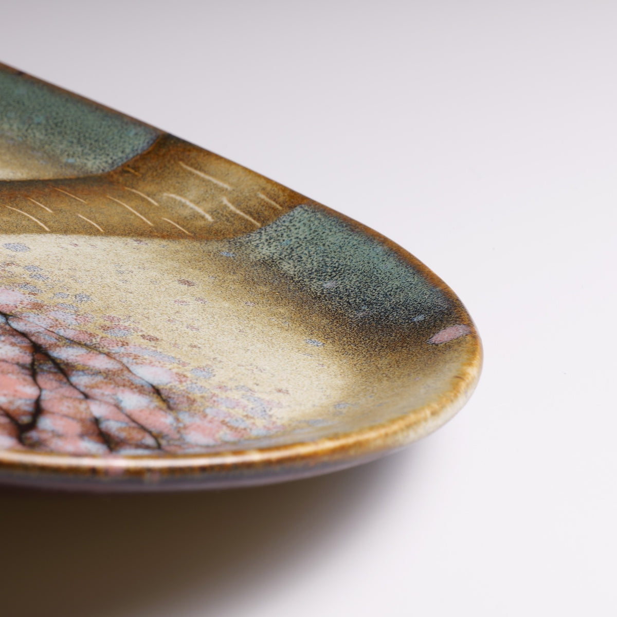 Detailed view of the Hanami handmade ceramic plate showing the golden rim, soft green glaze, and textured cherry blossom decoration.