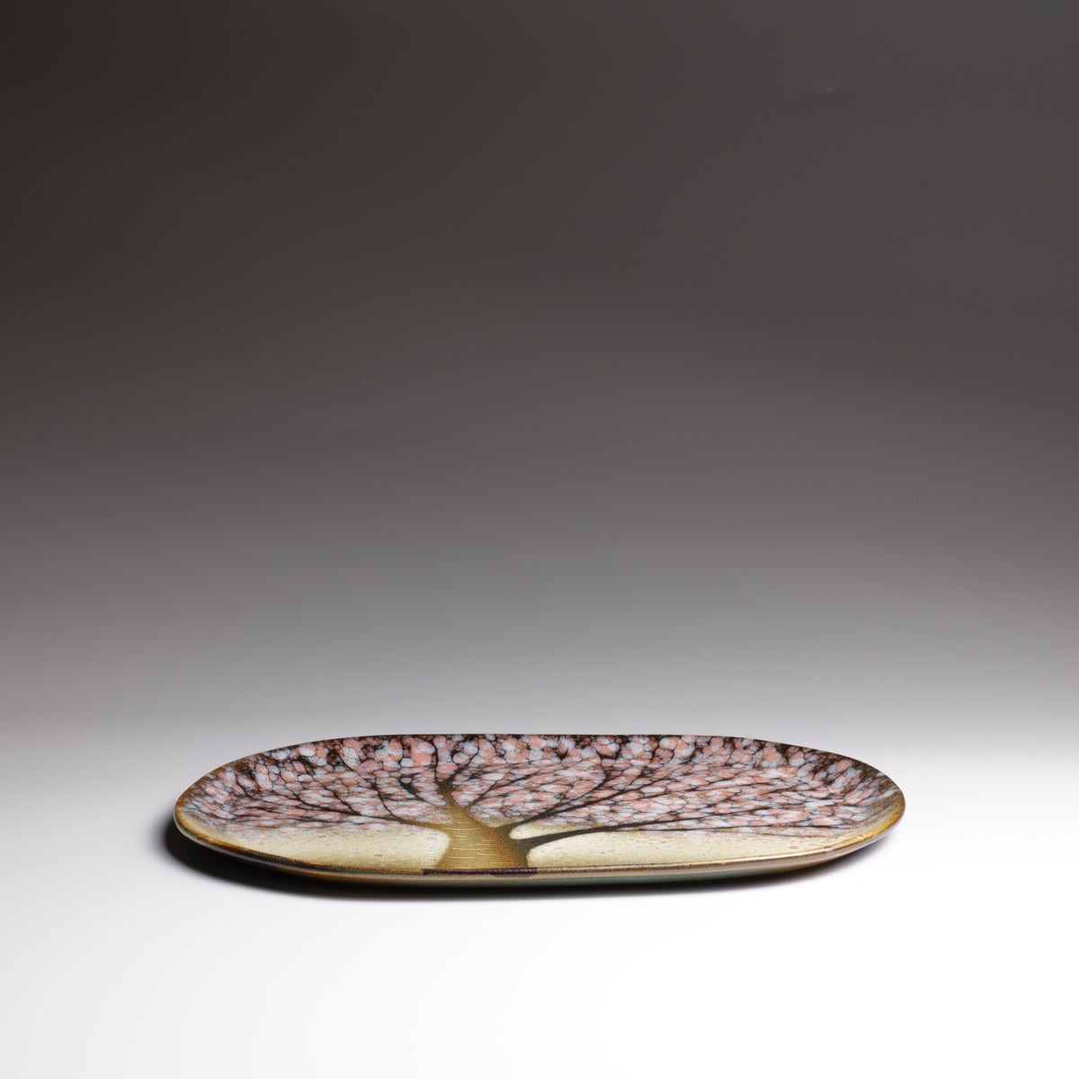 Low-angle side view of the Hanami handmade ceramic plate, showing its shallow curved profile, glossy rim, and cherry blossom pattern.
