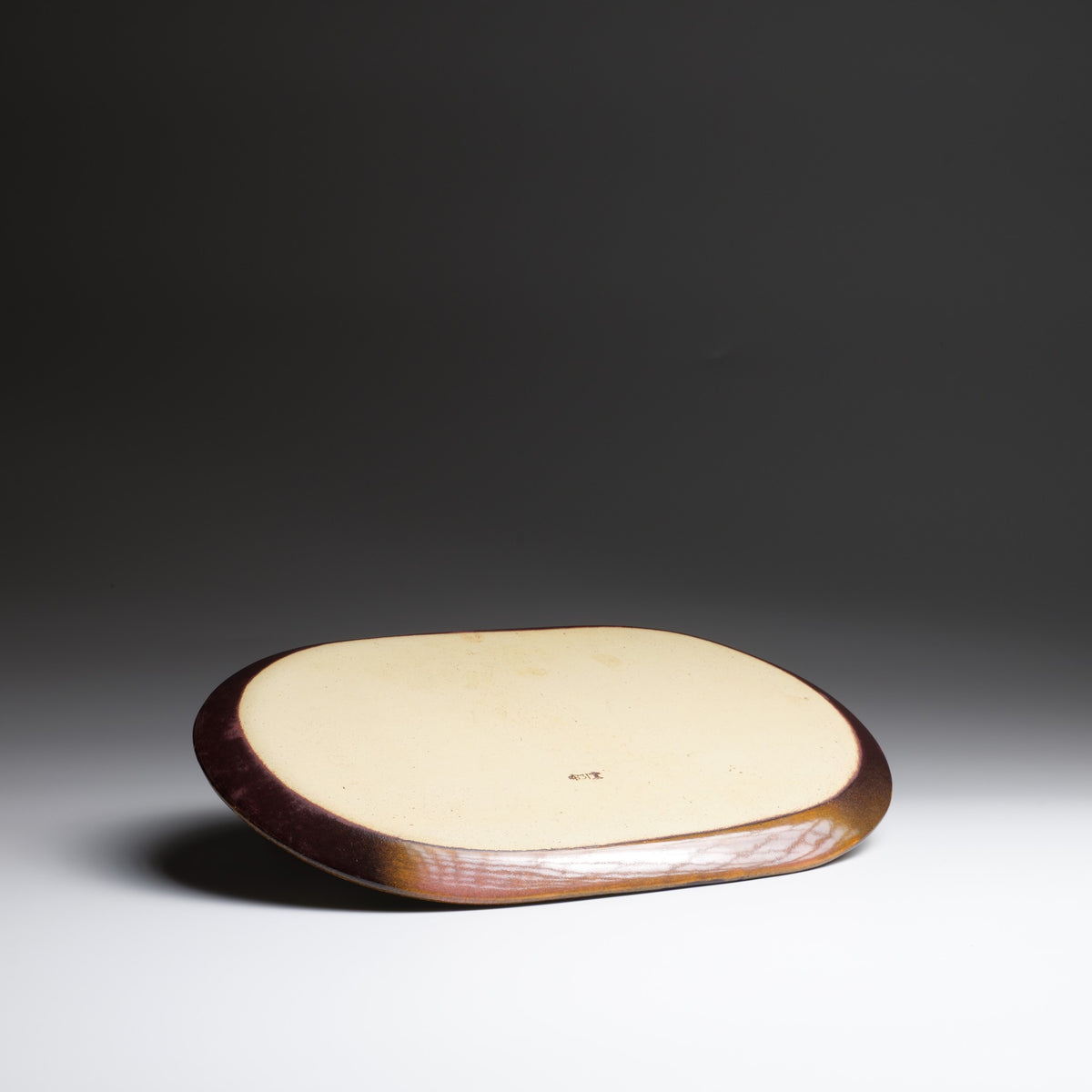 back view of the Hanami pink ceramic plate on a faded background