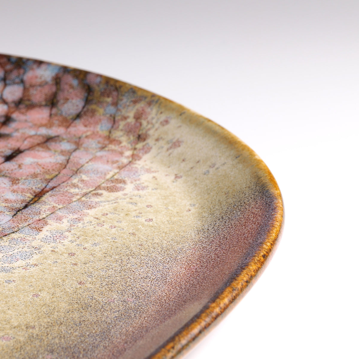 Detail of a Japanese ceramic plate with sakura decorations and pink shades.