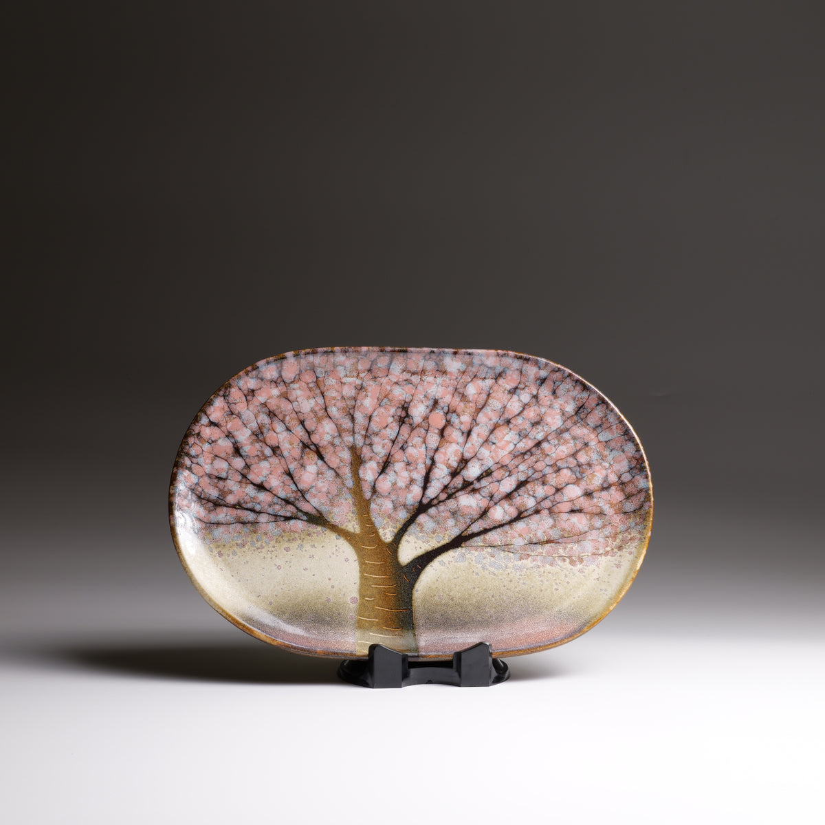 Japanese ceramic plate with pink sakura motif photographed on a faded background.