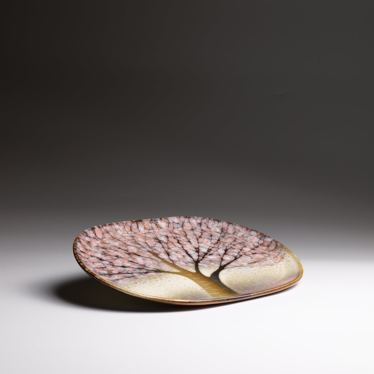 Handmade Japanese ceramic plate with sakura decorations and pink shades.