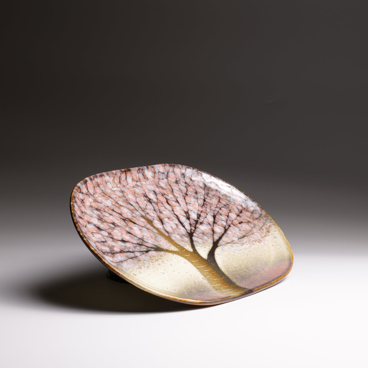 Japanese handmade ceramic plate with sakura decorations and pink shades on a fading background
