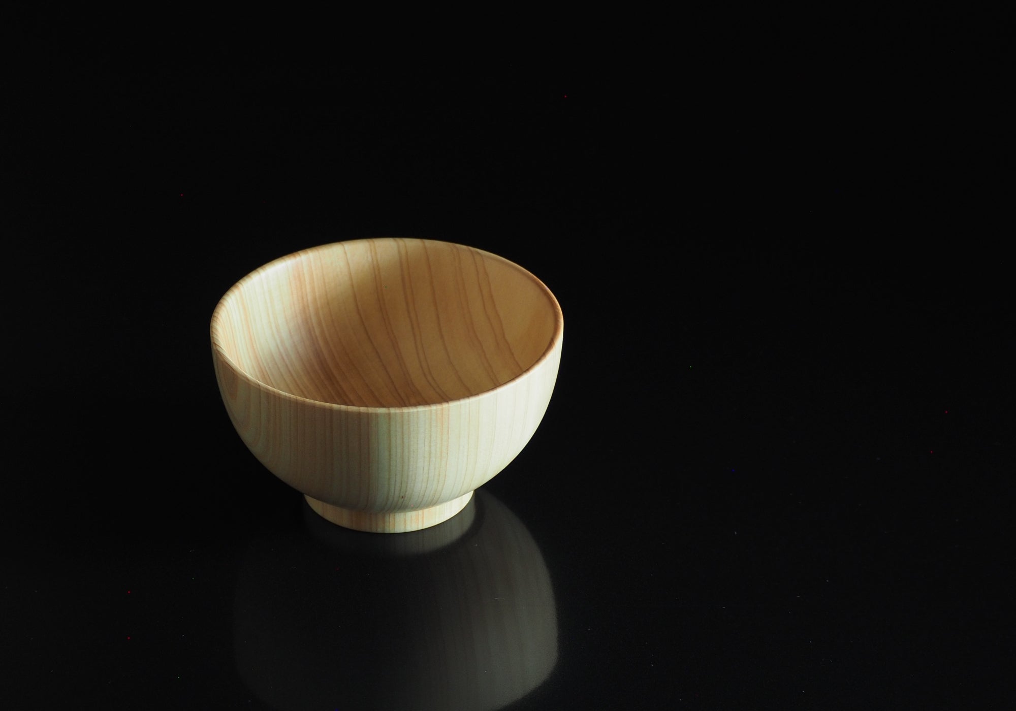 A Japanese wooden macha tea bowl on a black background. Tsukushi
