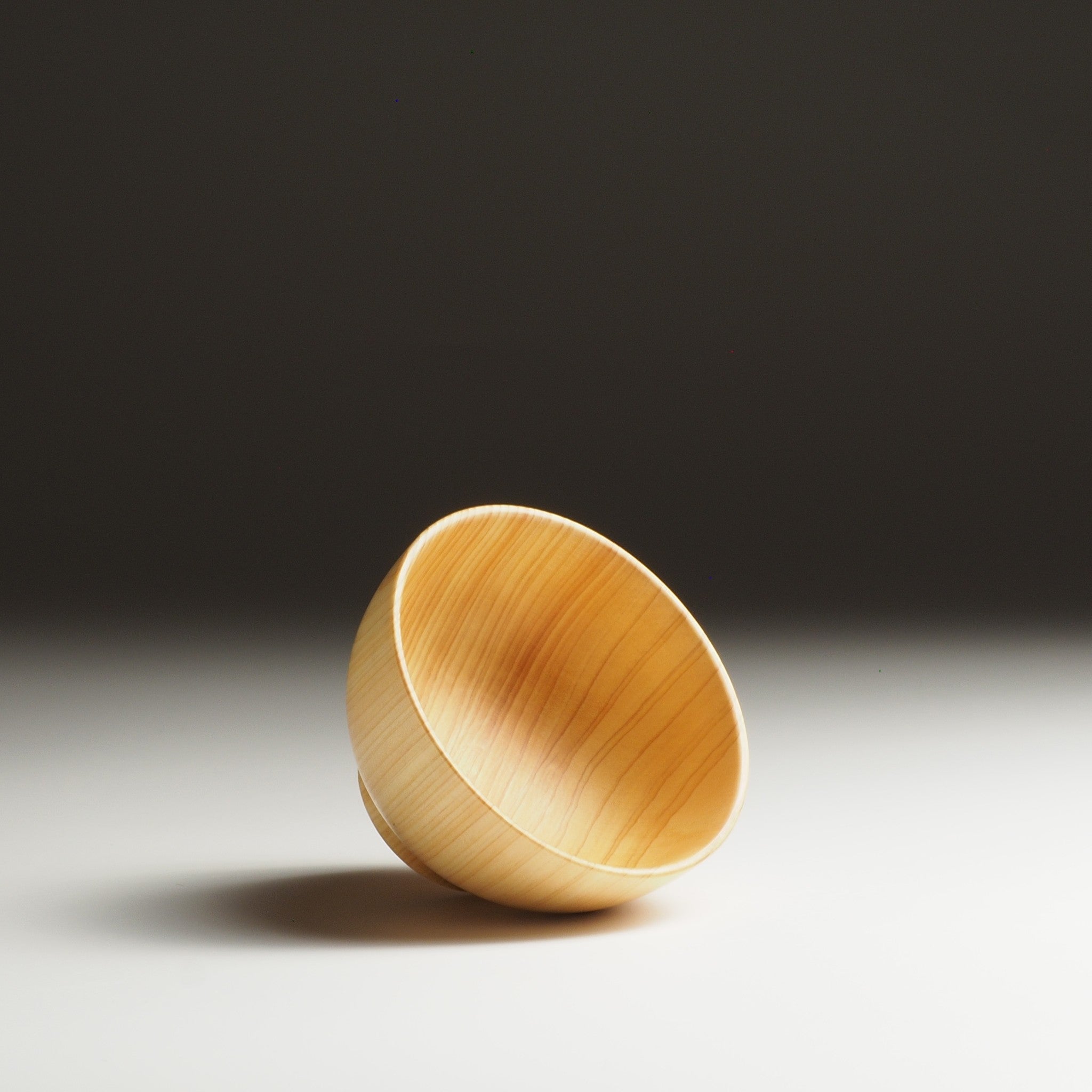 A front view of a Japanese wooden macha tea bowl on a beige background. Tsukushi