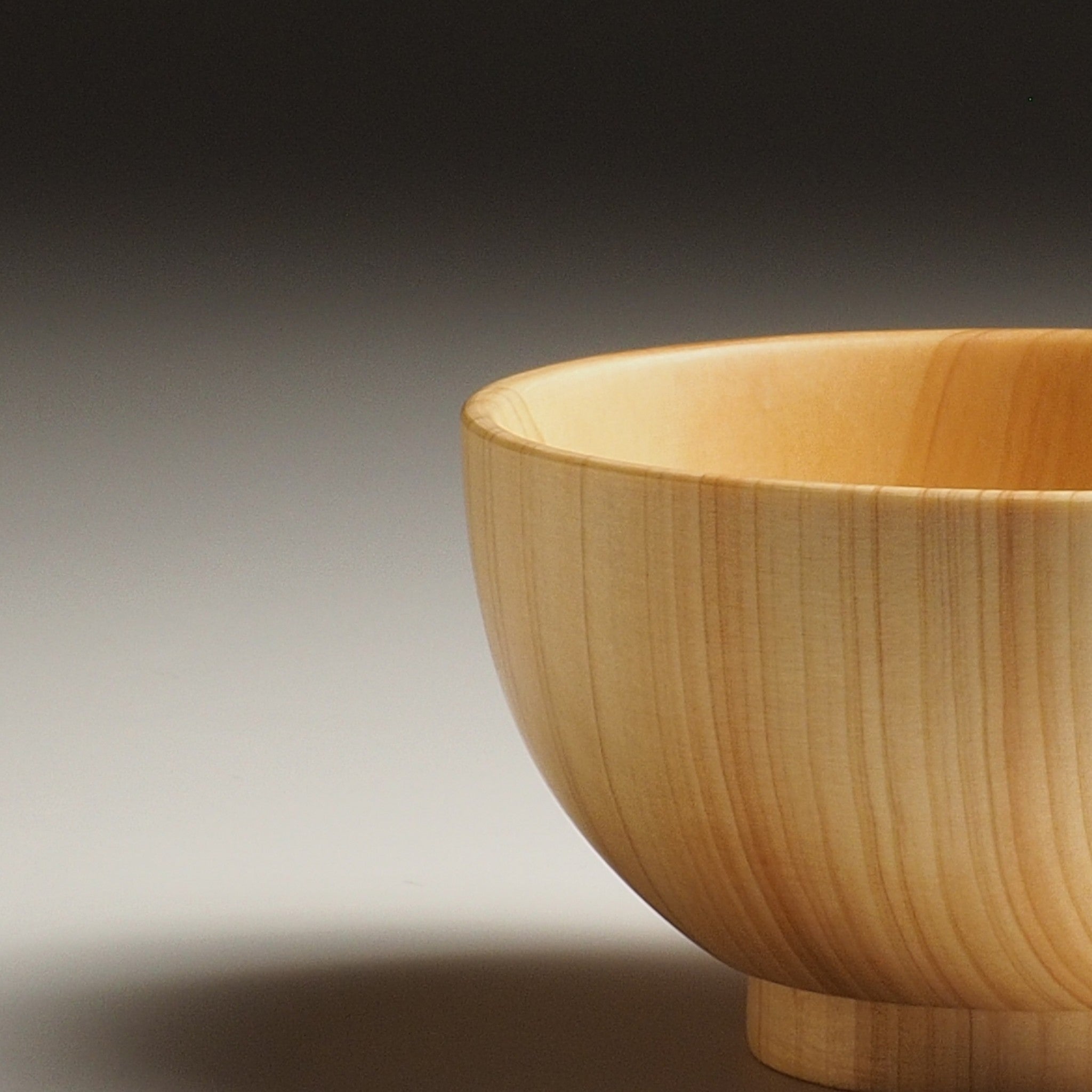 A Detail of a Japanese wooden macha tea bowl against a beige background. Tsukushi