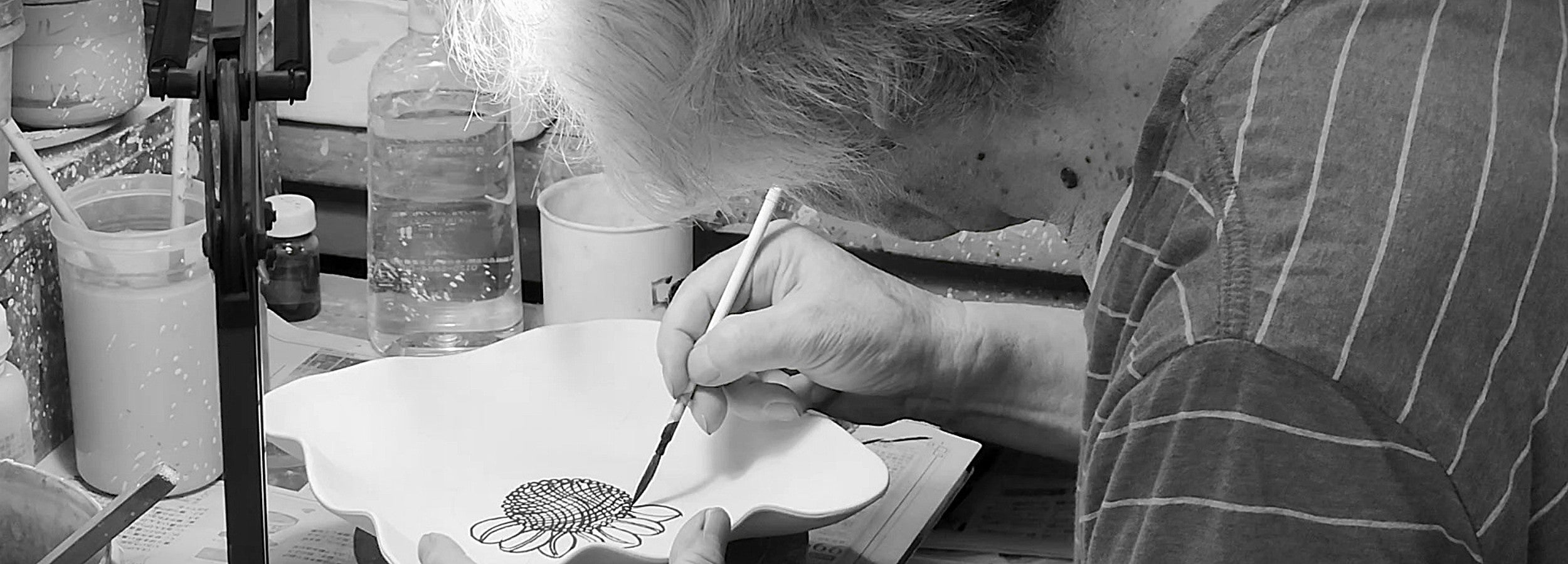 Taro Kojima painting a pottery plate. Tsukushi