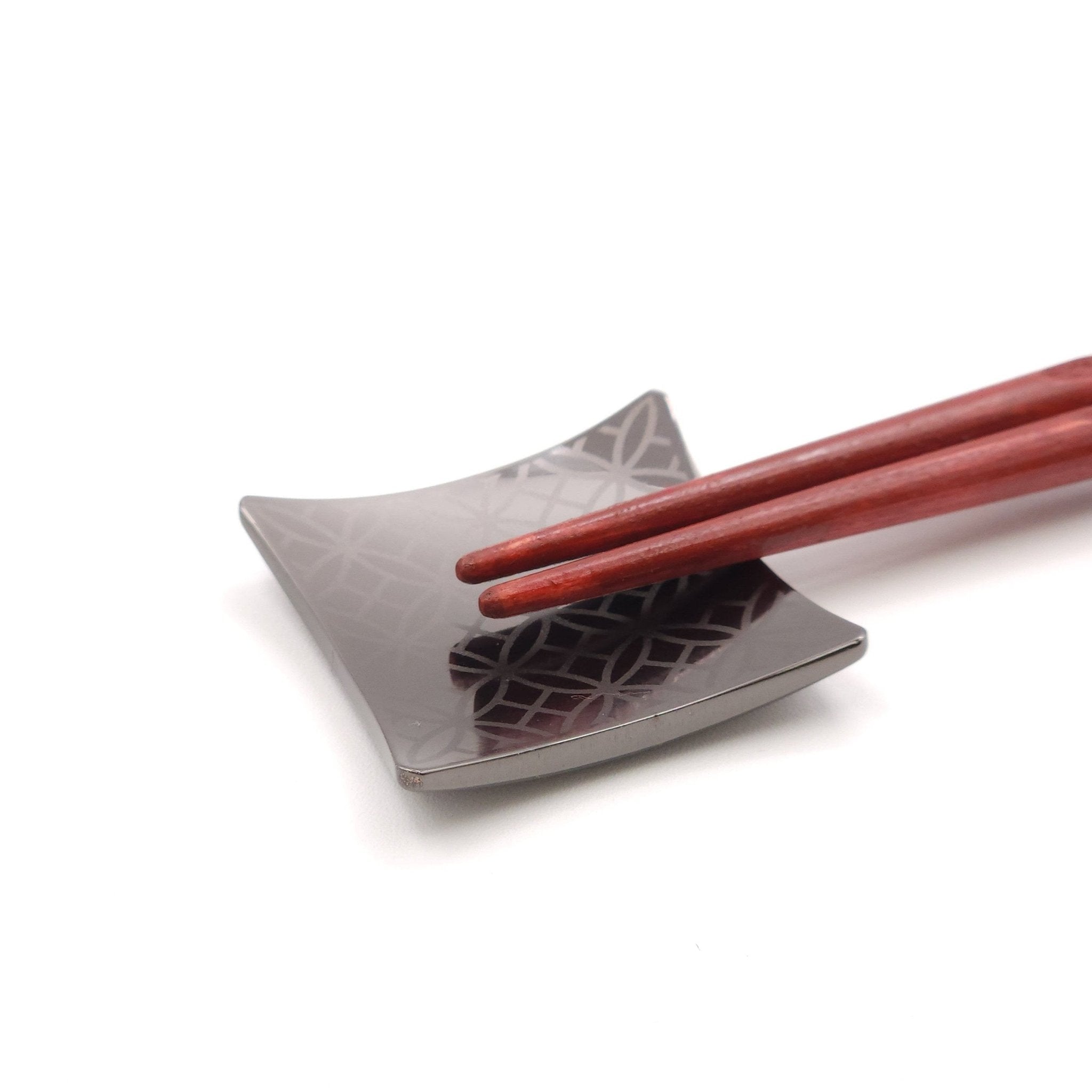 A Japanese Chopsticks rest in black metal with chopsticks on top.