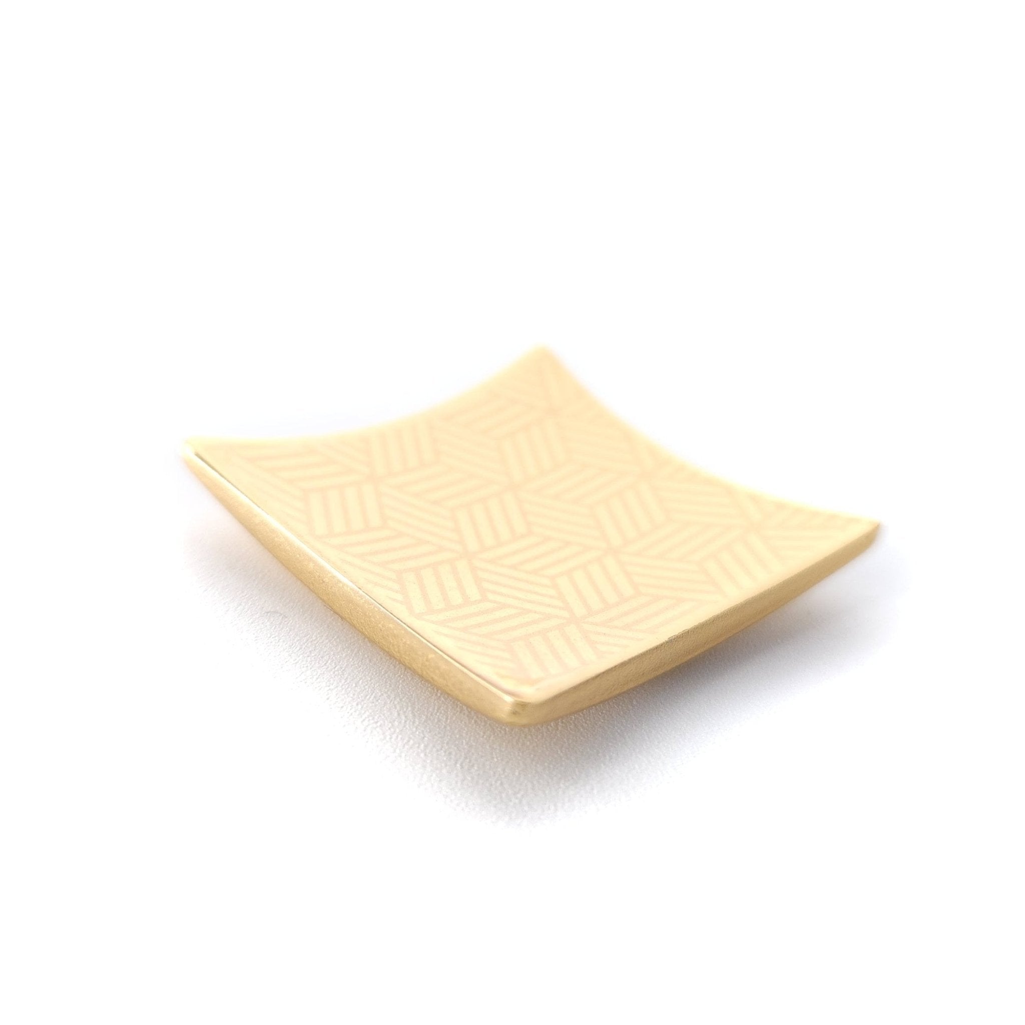 A Japanese Chopsticks rest in golden metal with lines pattern. Top side view.