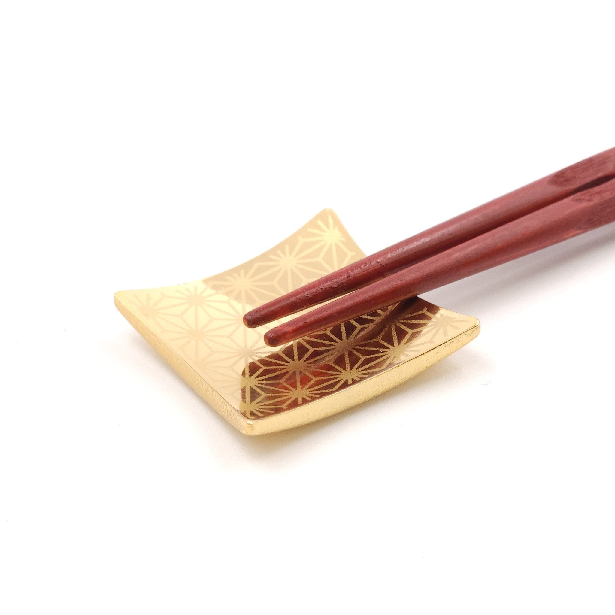A Japanese Chopsticks rest in golden metal with chopsticks on top