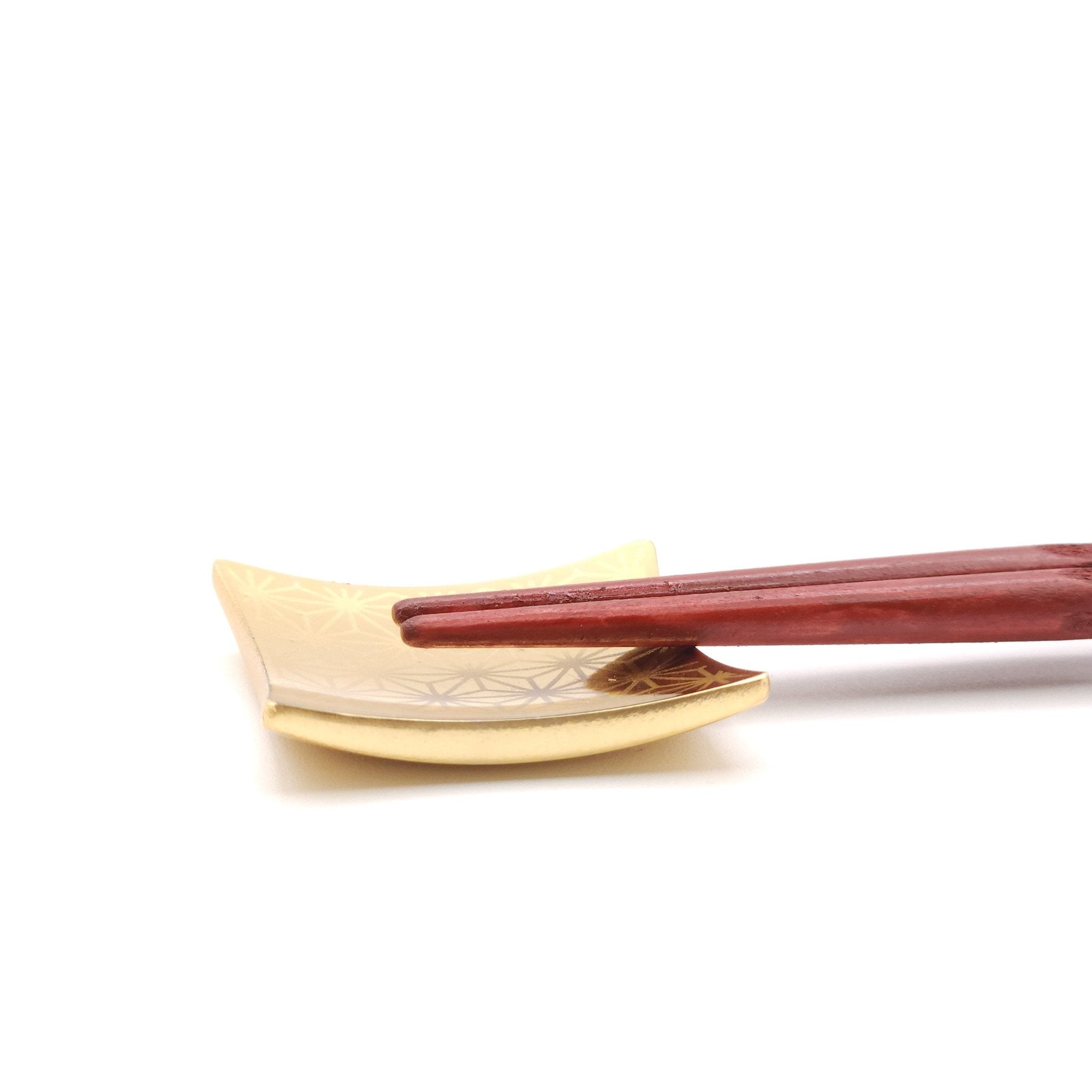 A Japanese Chopsticks rest in golden metal with chopsticks on top, side view.