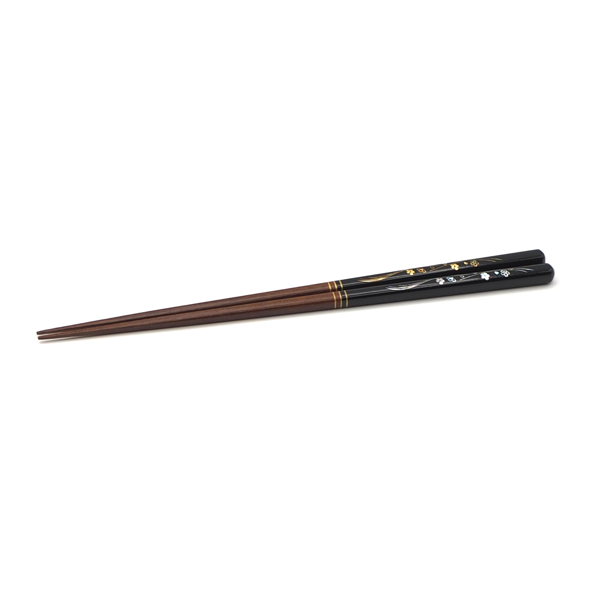 Side view of black Japanese chopsticks with cherry blossom motifs