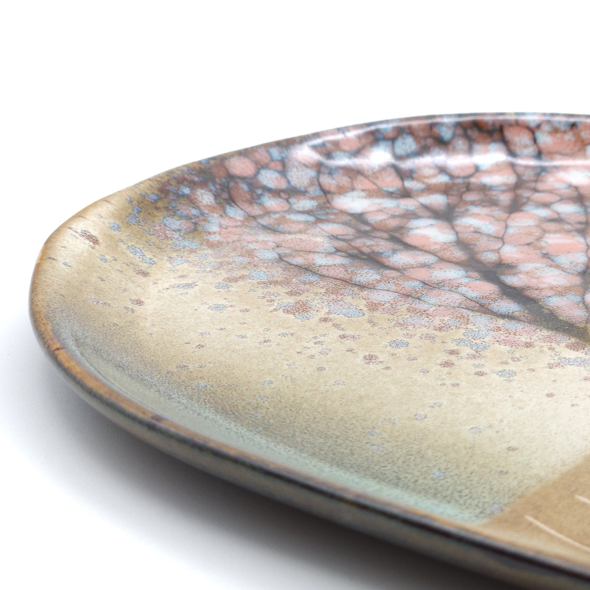 A detail of a Japanese plate made of pottery with cherry blossoms motif in green background.