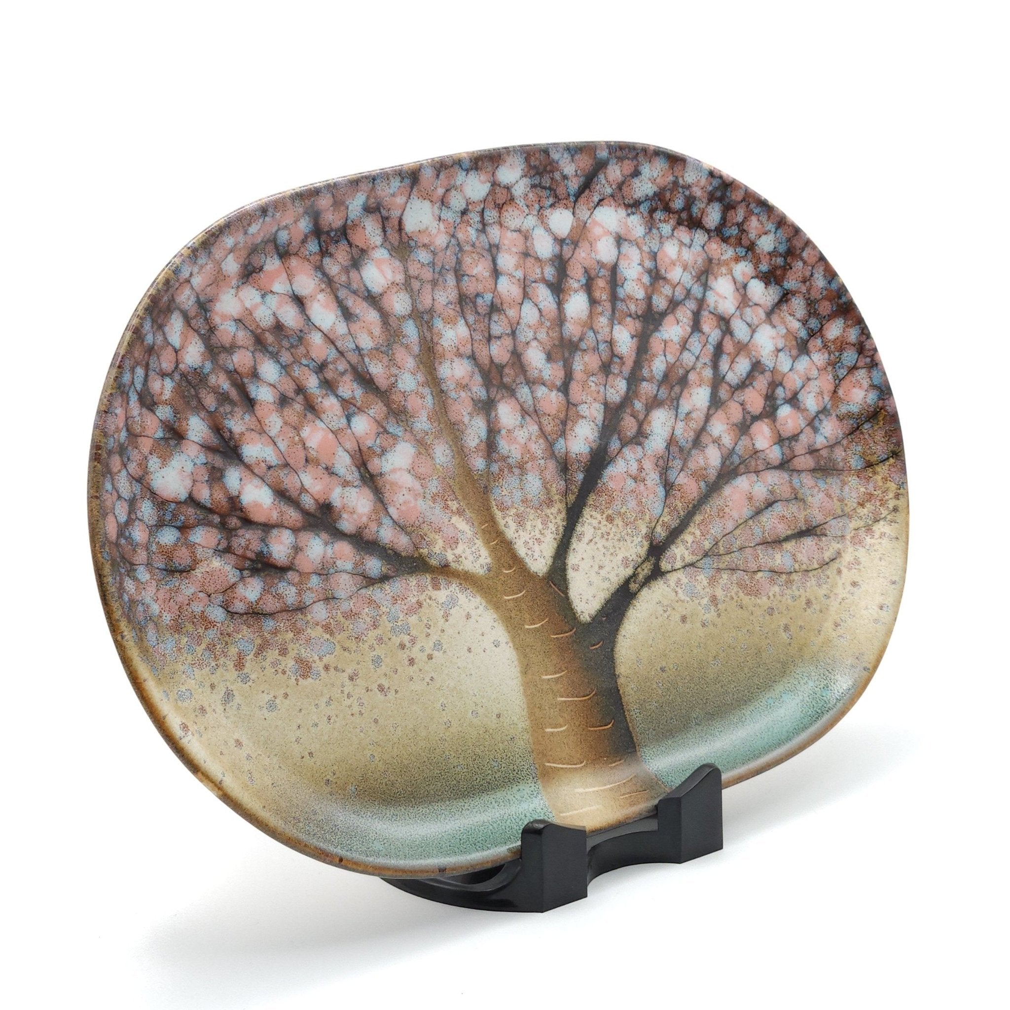 A Japanese plate made of pottery with cherry blossoms motif in green background. Lateral view