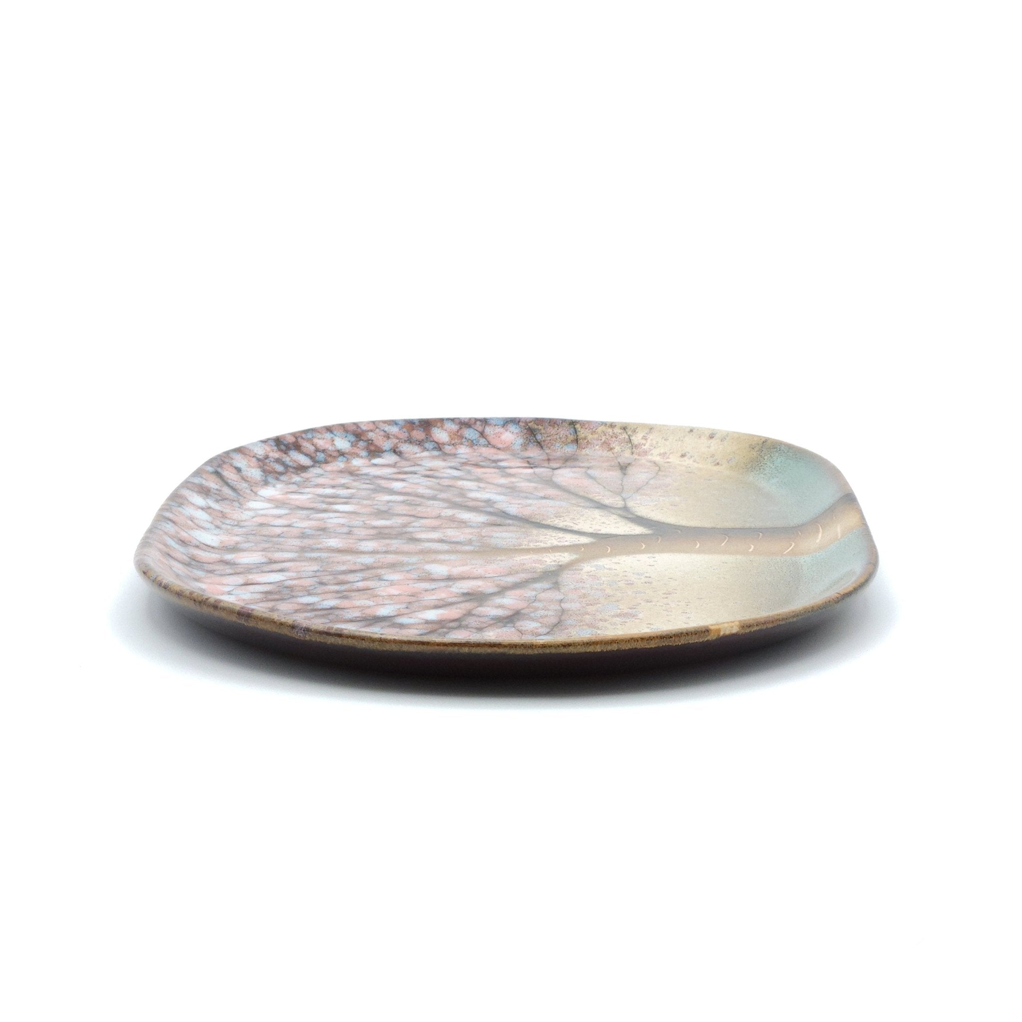 Side view of a Japanese plate made of pottery with cherry blossoms motif in green background.