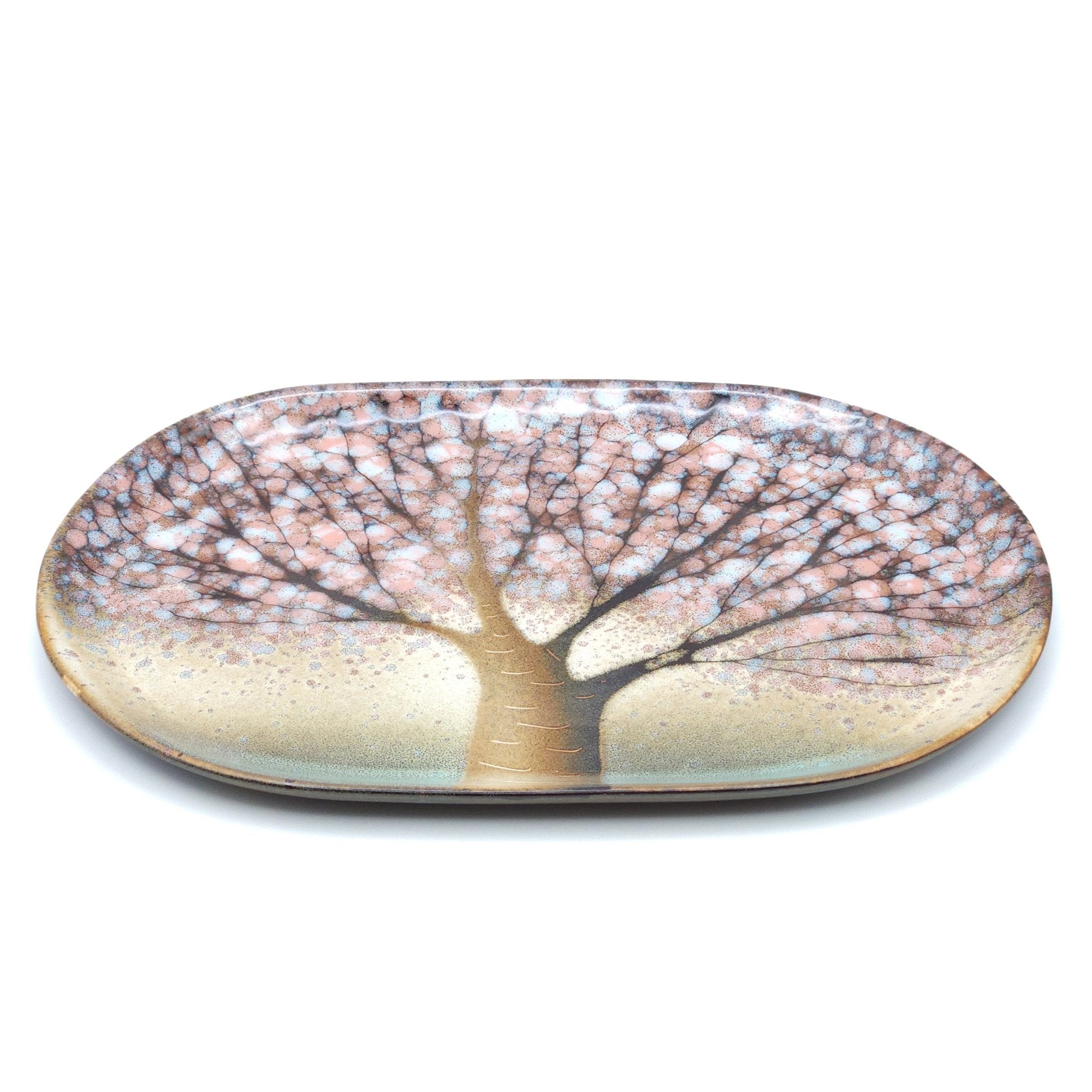 A Japanese plate made of pottery with cherry blossoms motif in green background. Top long side view