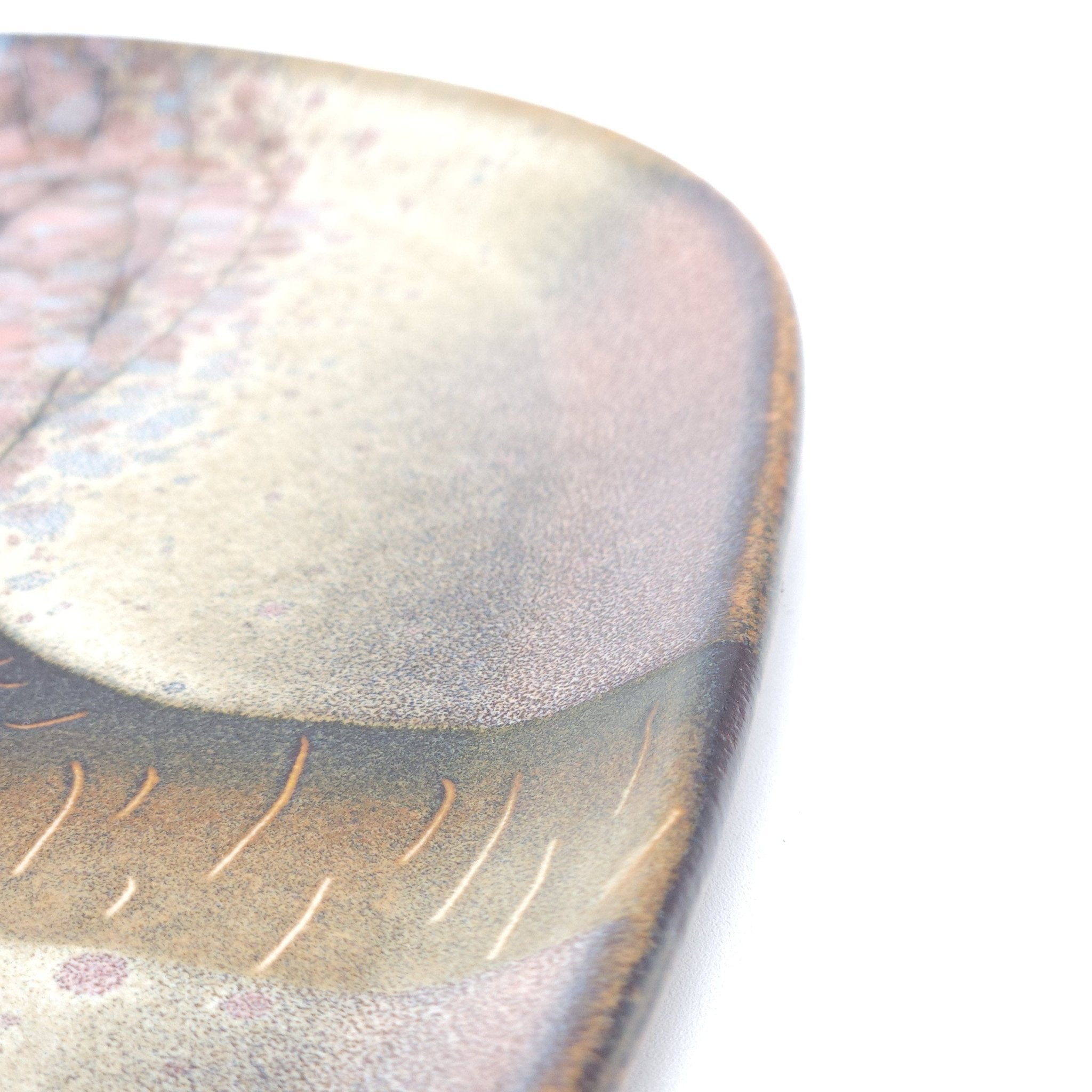 A detail of a Japanese plate made of pottery with cherry blossoms motif in pink background.