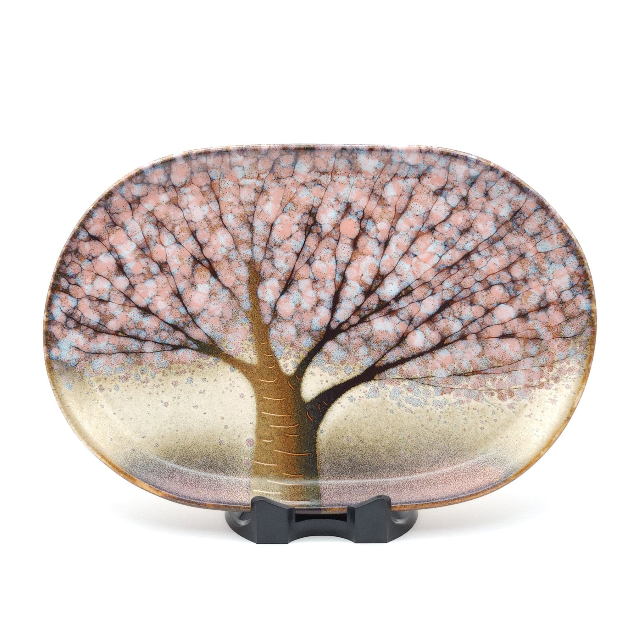 A Japanese plate made of pottery with cherry blossoms motif in  pink background. Front view