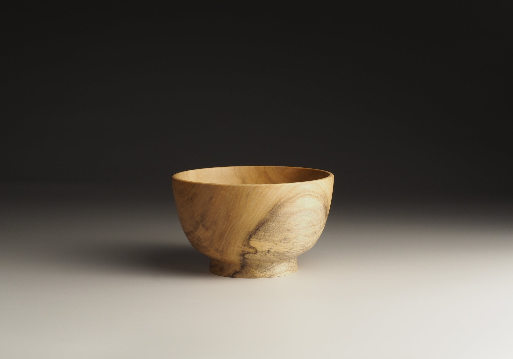 Japanese elm handcrafted wooden bowl on black gradation background. Tsukushi
