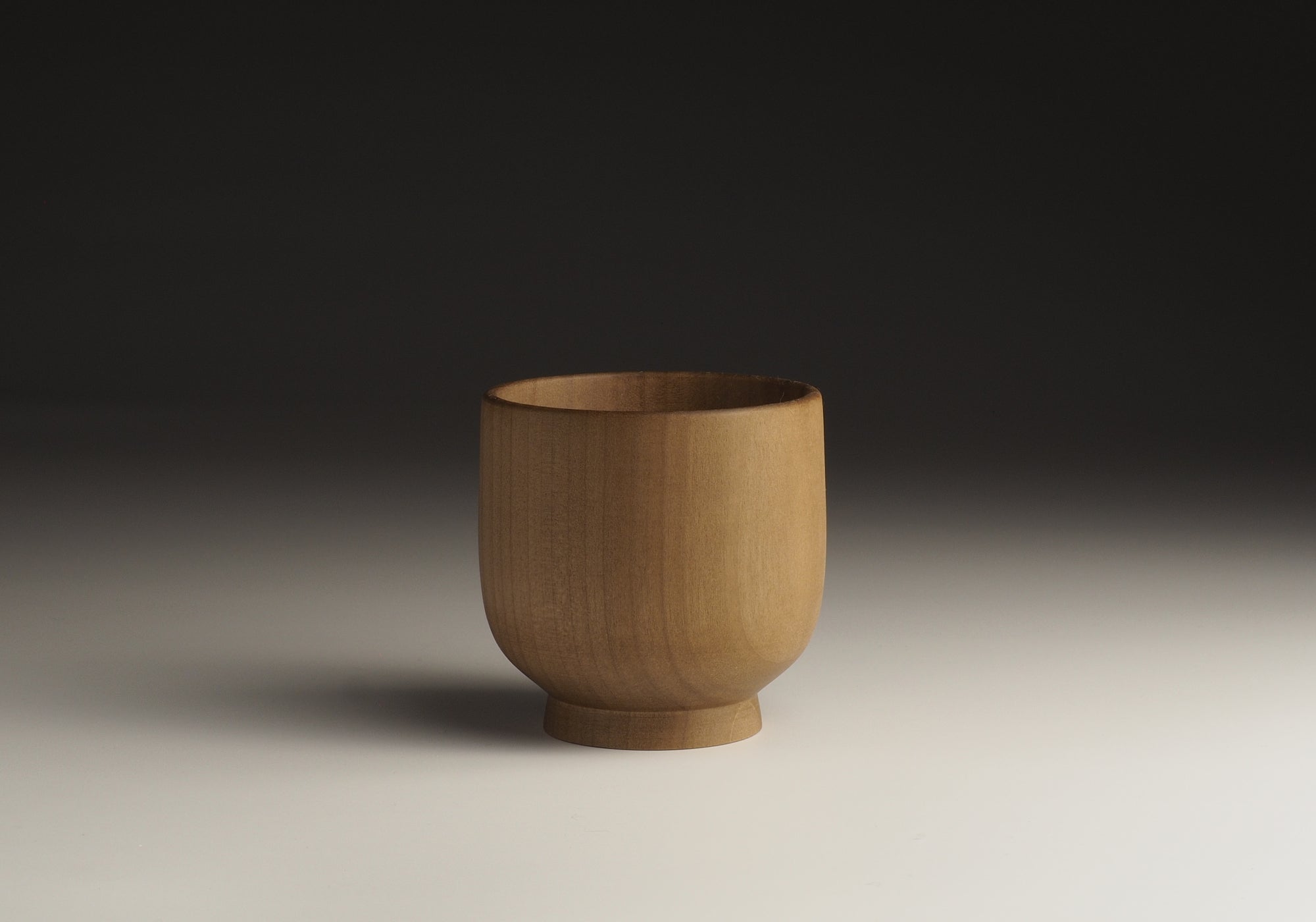 A Japanese handcrafted Wooden Teacup on a beige gradient background . Tsukushi