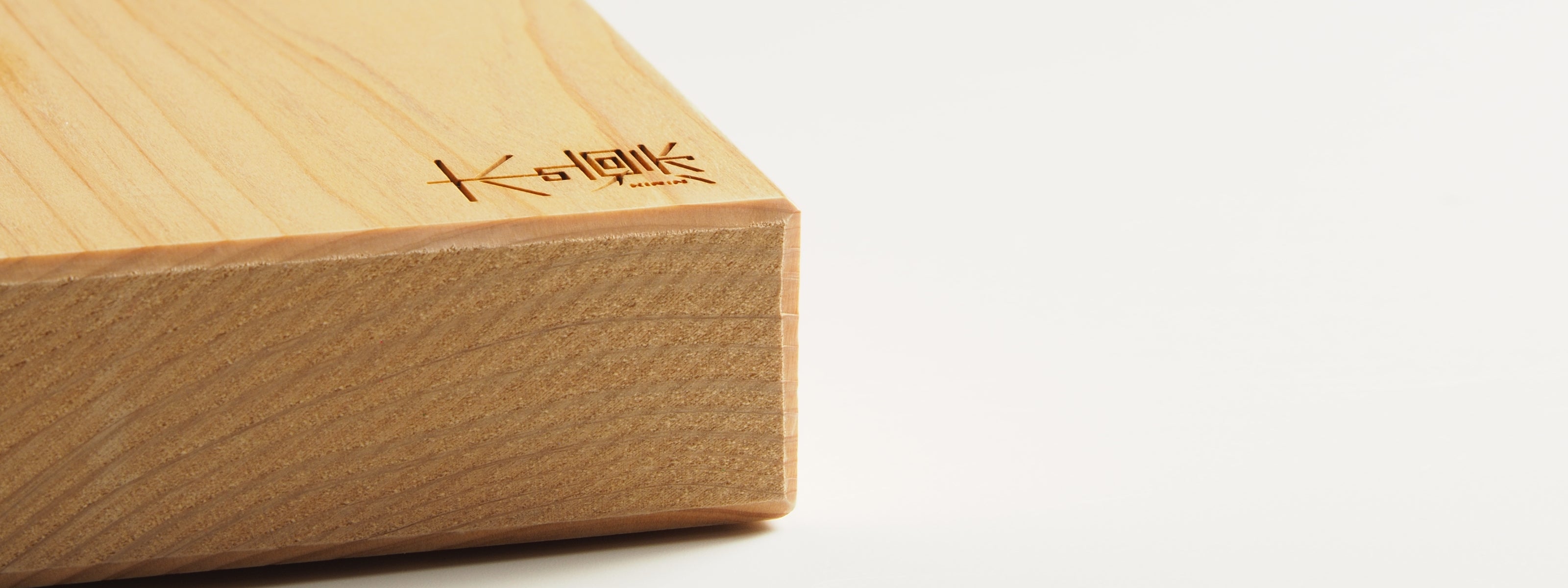 Close-up of a Japanese cutting board with engraved text on a white background. Tsukushi