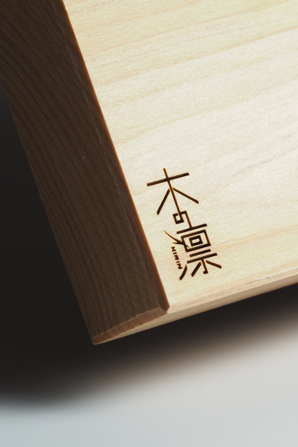 Close up of a manaita with engraved text on a light background. Tsukushi