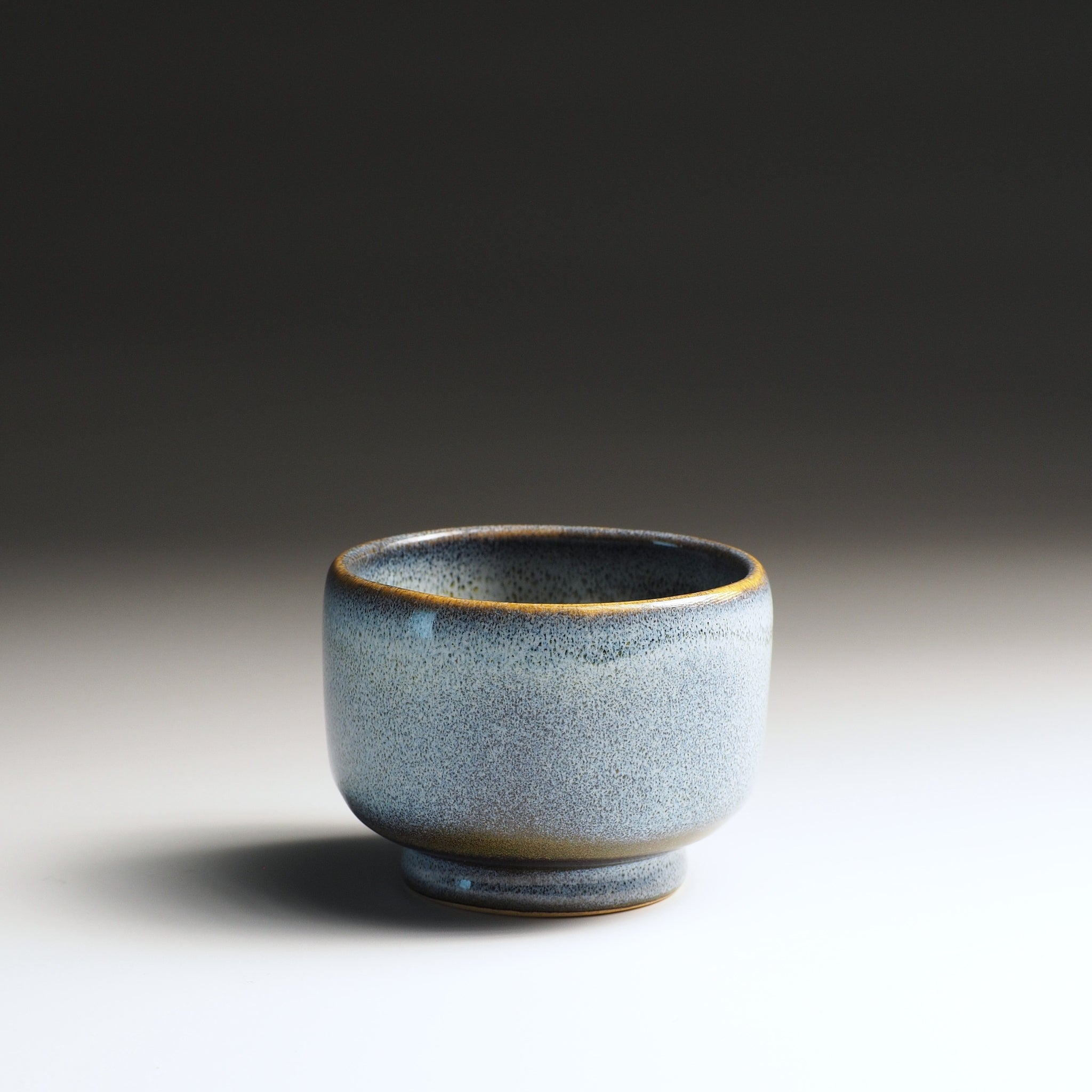 Light-blue ceramic yunomi teacup on a gradient background
