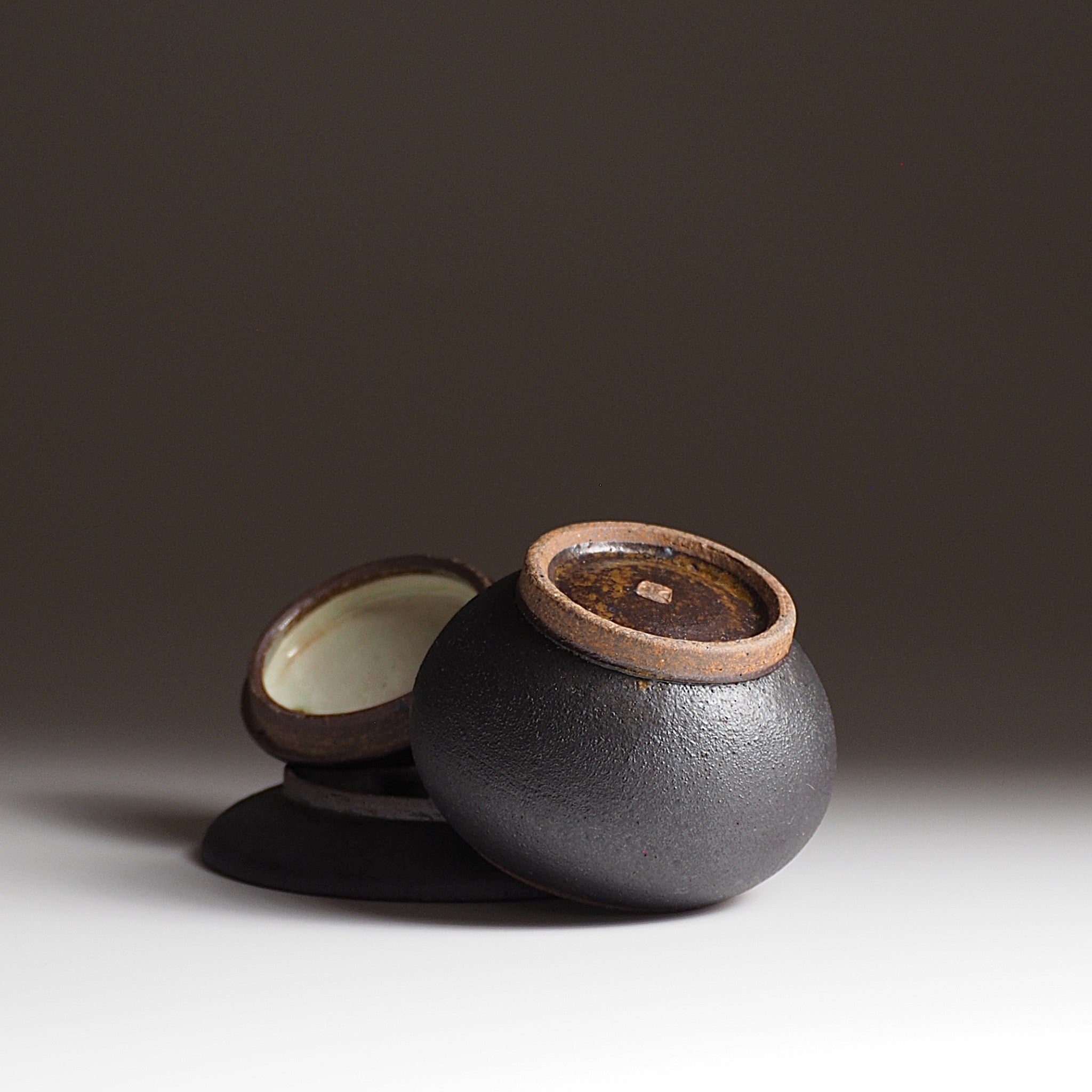 Bottom view of a chawanmushi bowl made from unglazed pottery in black. Tsukushi