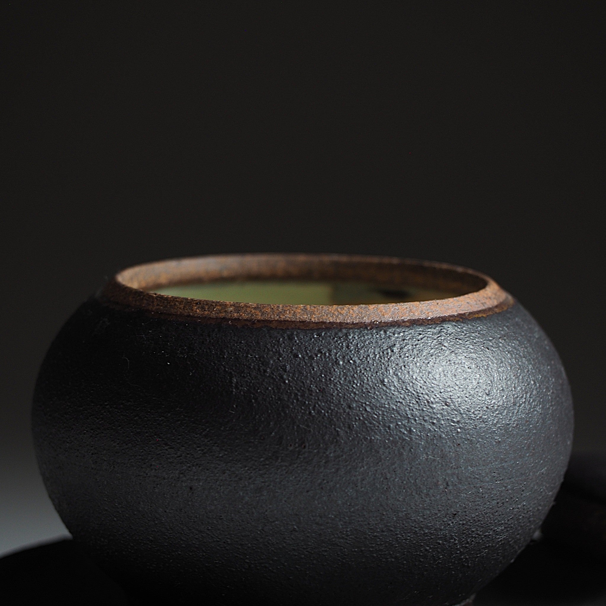 Detail of a Japanese pottery black chawanmushi bowl. Tsukushi