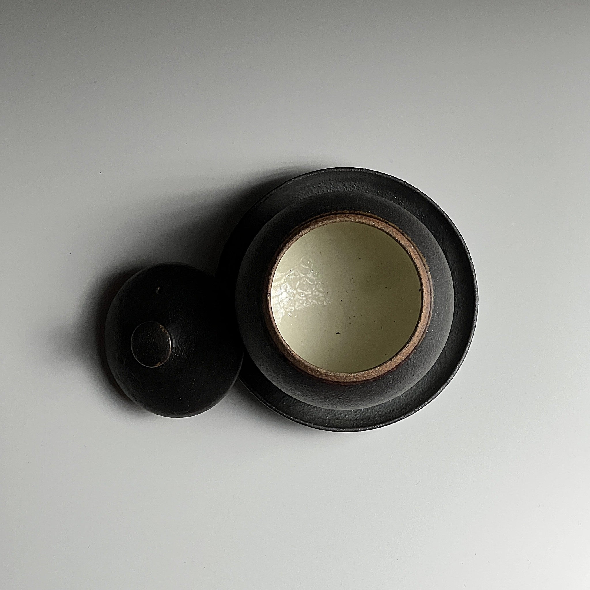 Top view of a black Japanese ceramic chawanmushi bowl with lid and saucer. Tsukushi