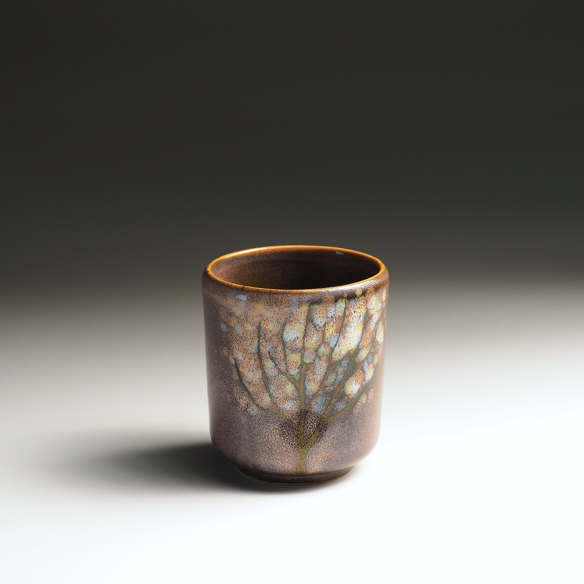 Japanese yunomi teacup with a pink glaze surface and floral decorations. Tsukushi