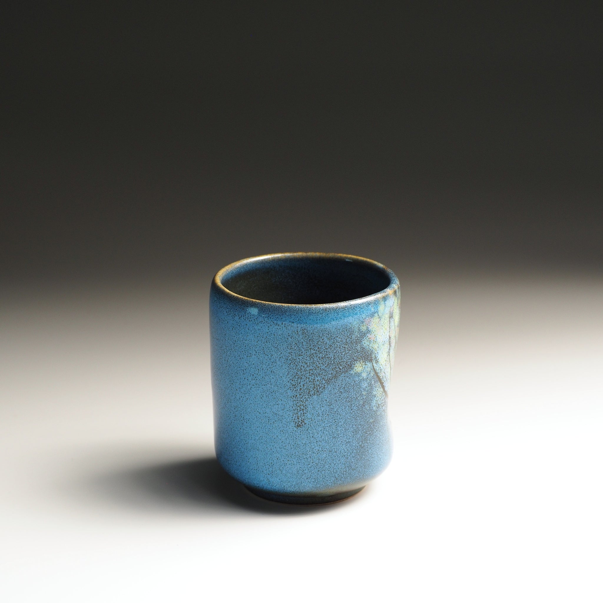Blue yunomi cup with wabi sabi glaze and floral decorations. Tsukushi