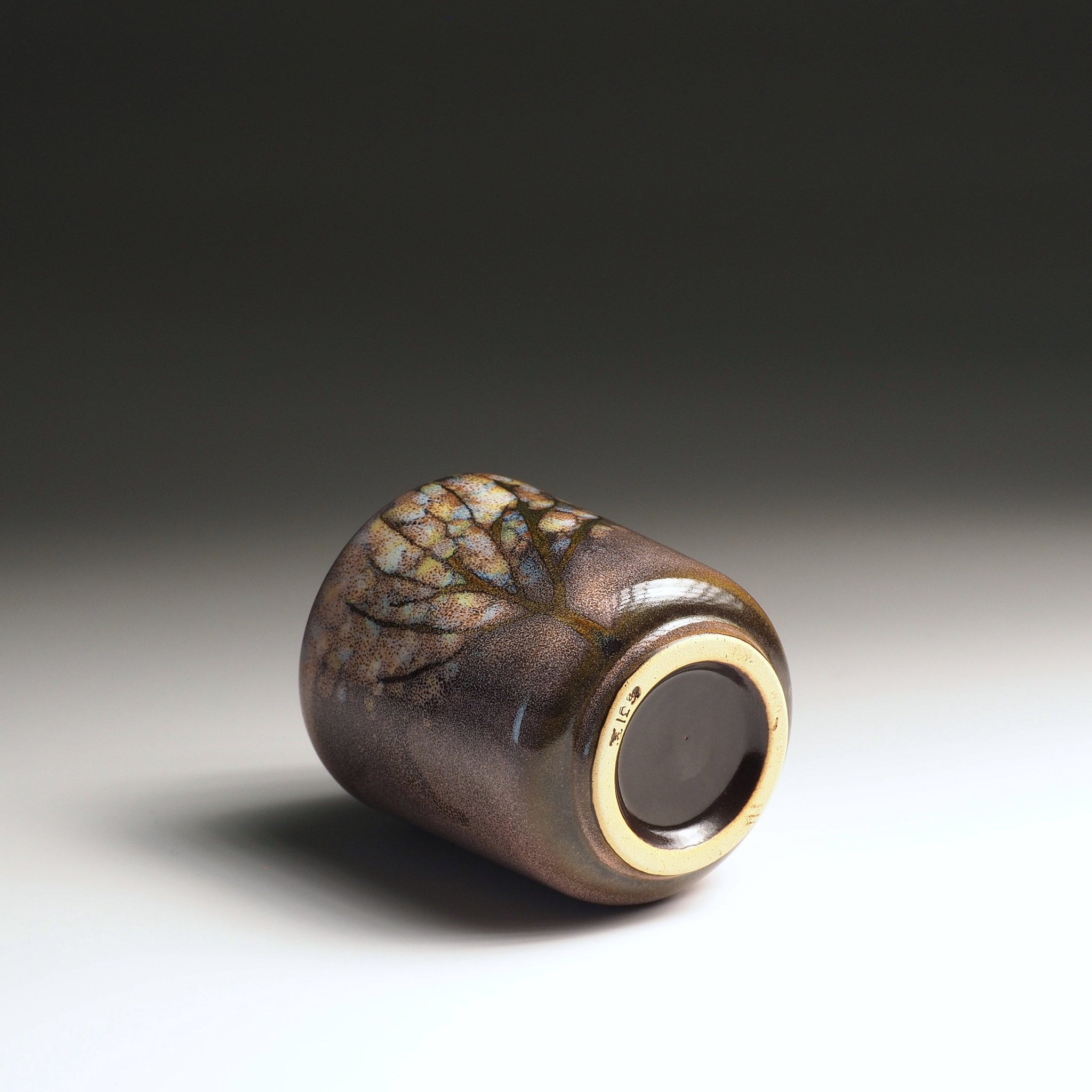 Bottom view of a handmade Japanese ceramic yunomi teacup showing the foot ring and wabi-sabi glaze with soft pink-brown tones, Tsukushi
