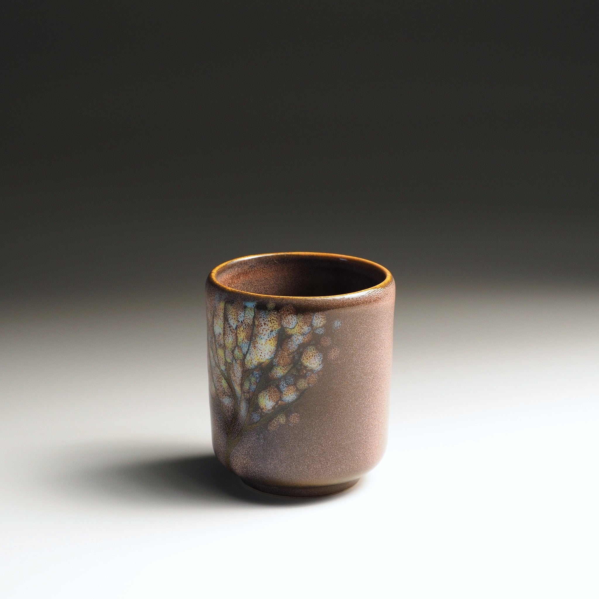 Front view of a handcrafted Japanese yunomi teacup in soft pink wabi-sabi glaze with subtle iridescent decoration, Tsukushi