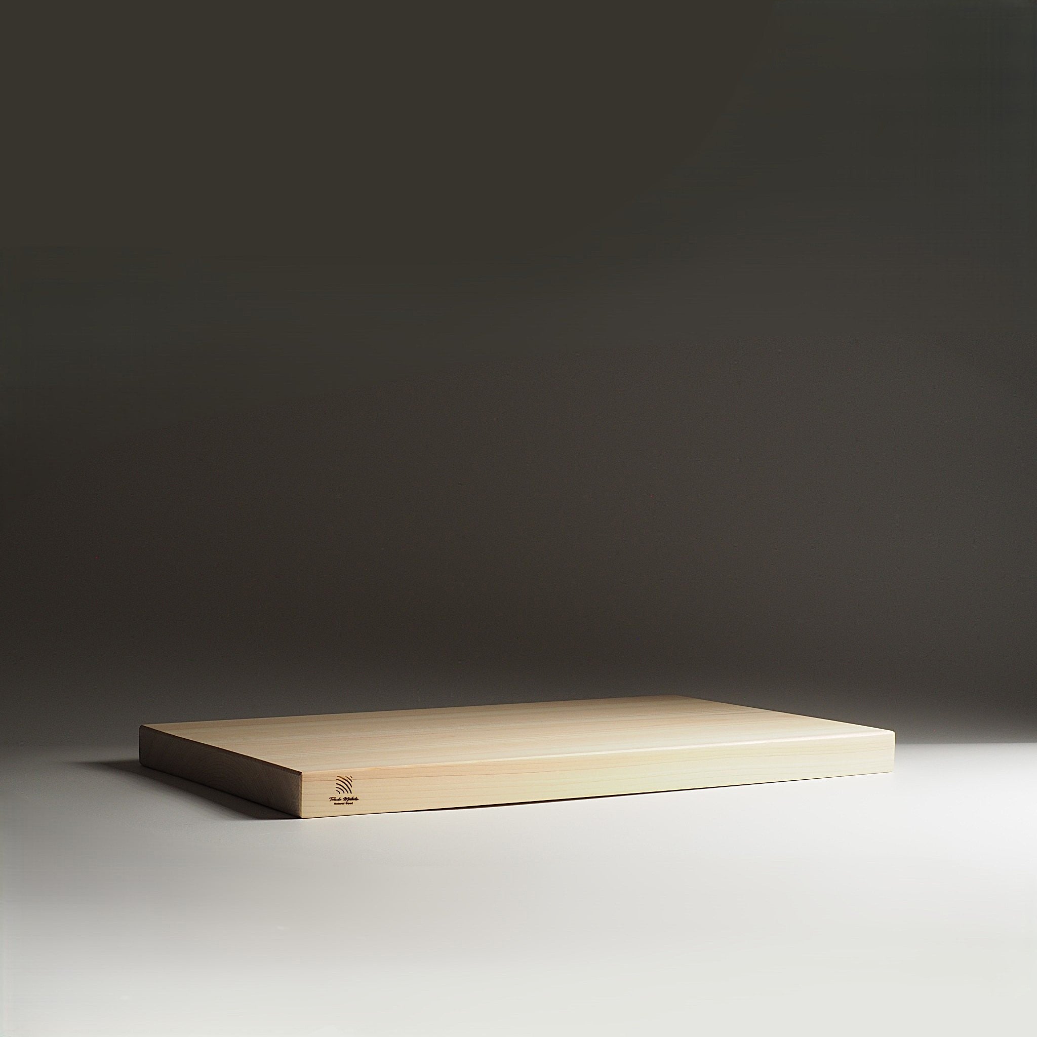 Japanese wooden cutting board on a dark gray background. Tsukushi