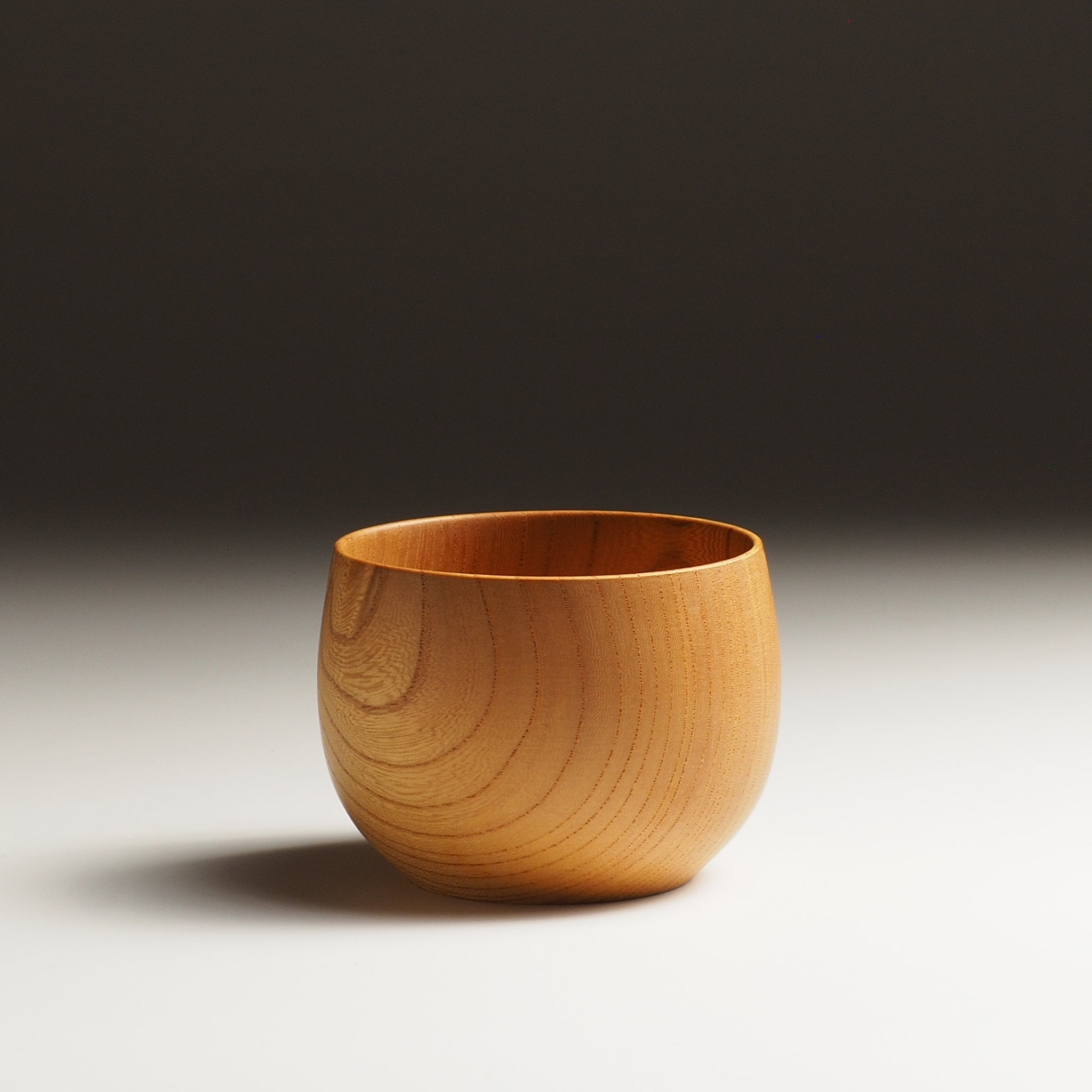 A Japanese wooden cup on a beige background. Tsukushi