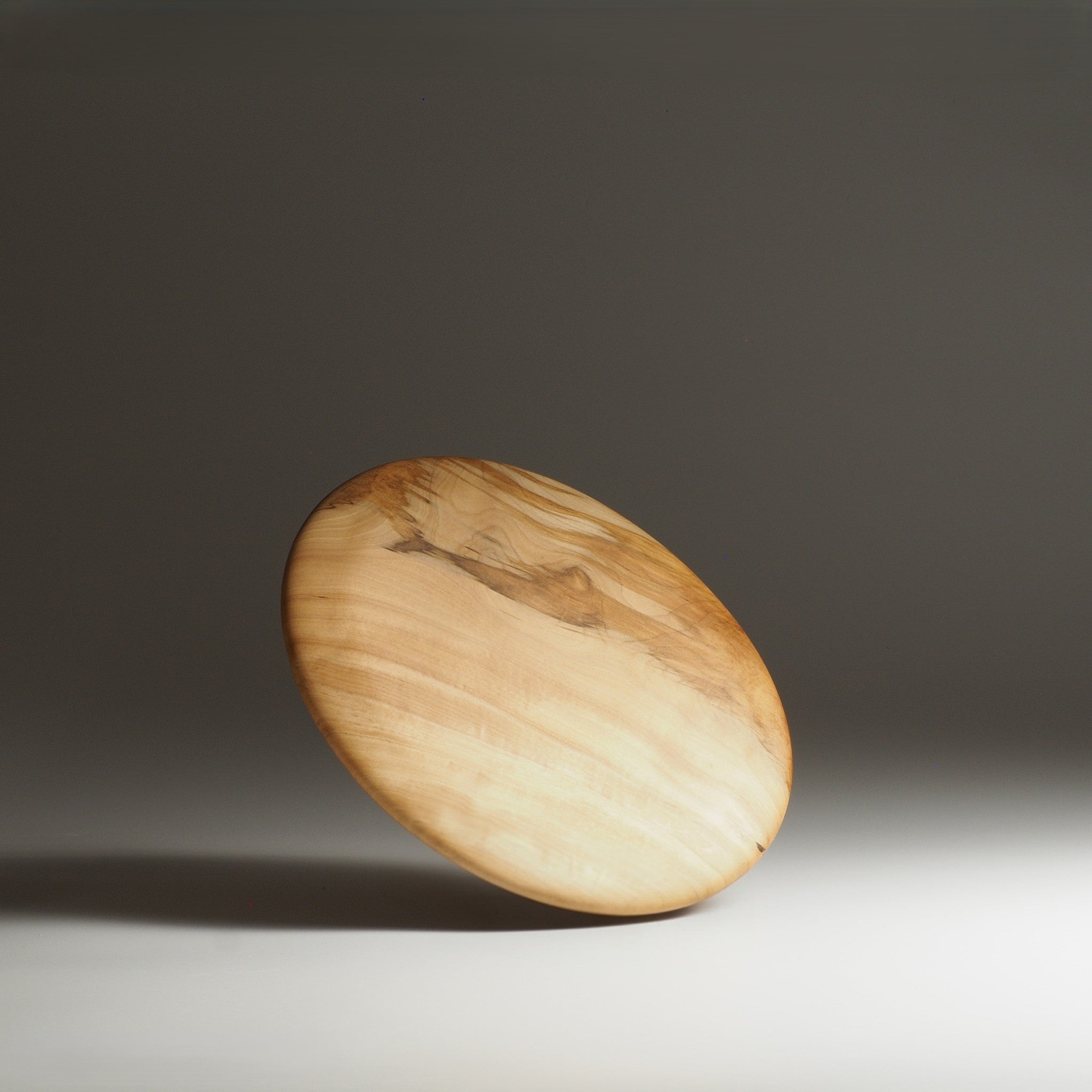 Back side view of Japanese wooden dinner plate on a beige background. Tsukushi