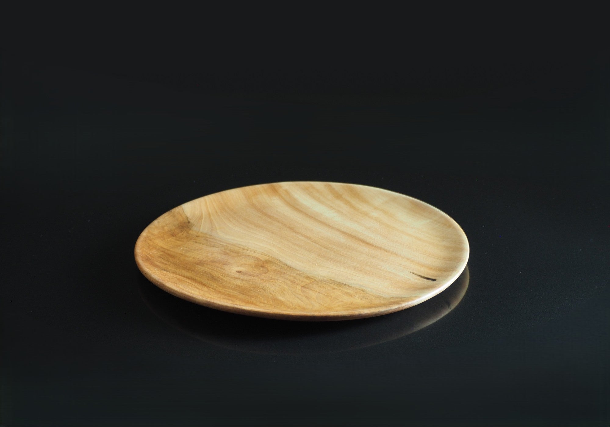 Japanese wooden plate on a black reflective surface. Tsukushi