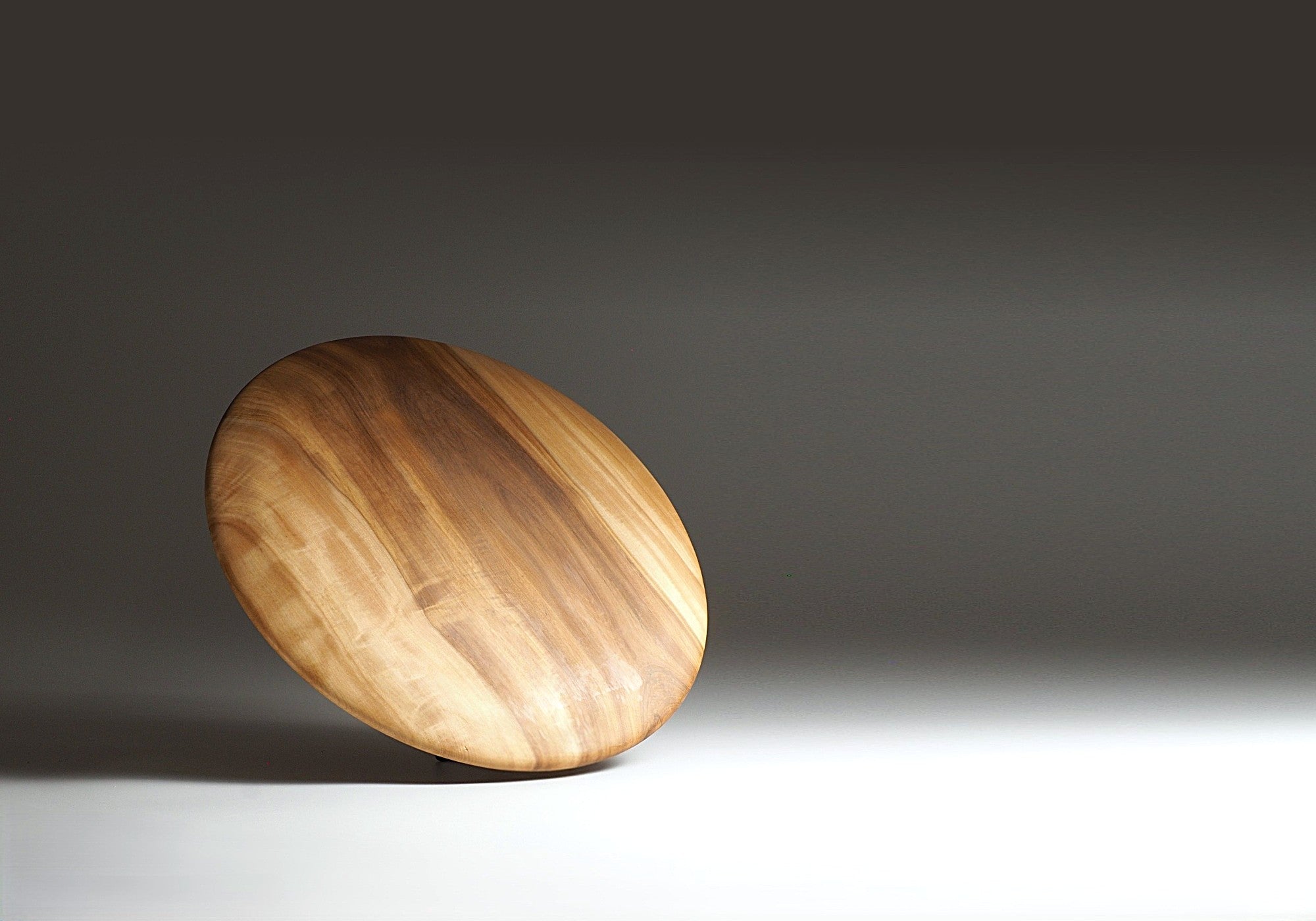 Japanese wood plate showing the back on a dark gray background. Tsukushi