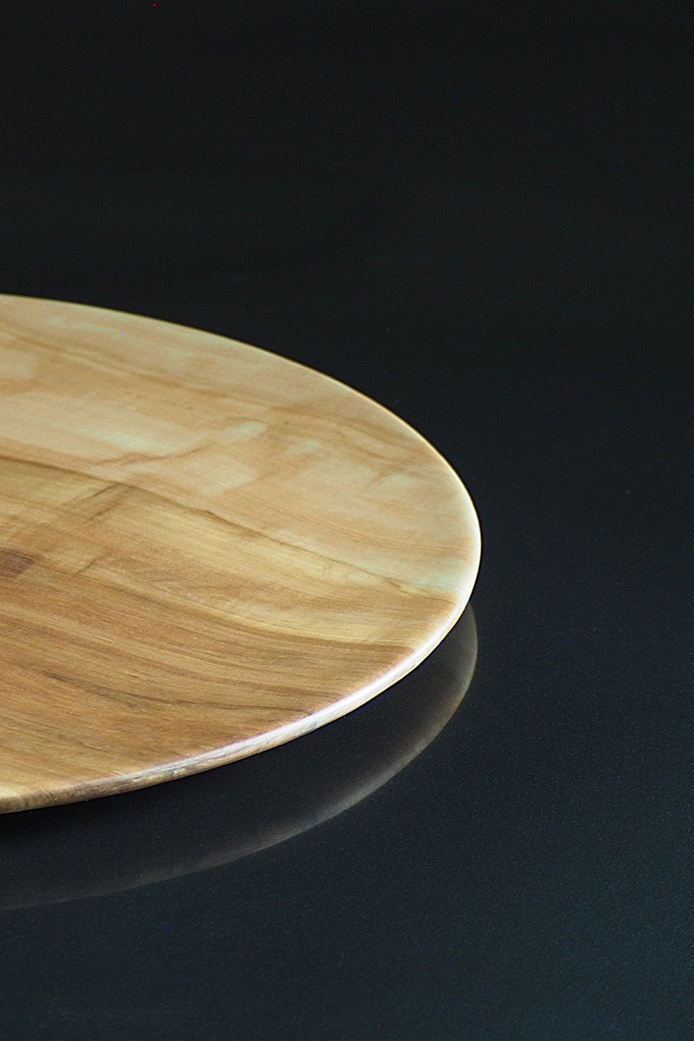 Wooden dinner plate on a reflective black surface. Tsukushi