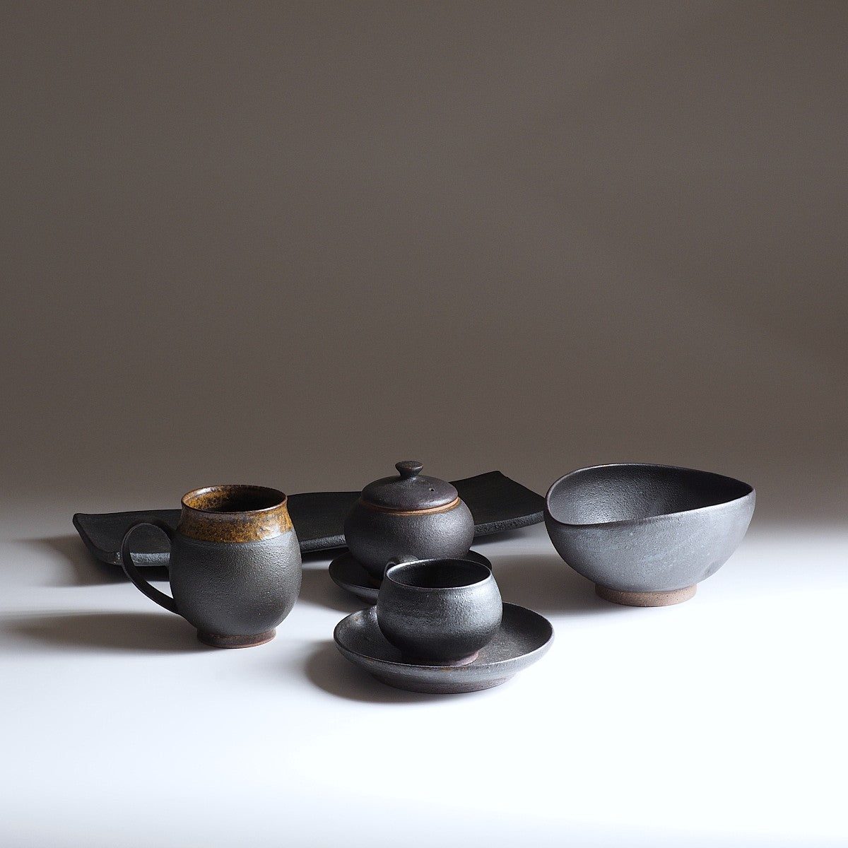 Japanese handcrafted black ceramic collection beige background, Tsukushi