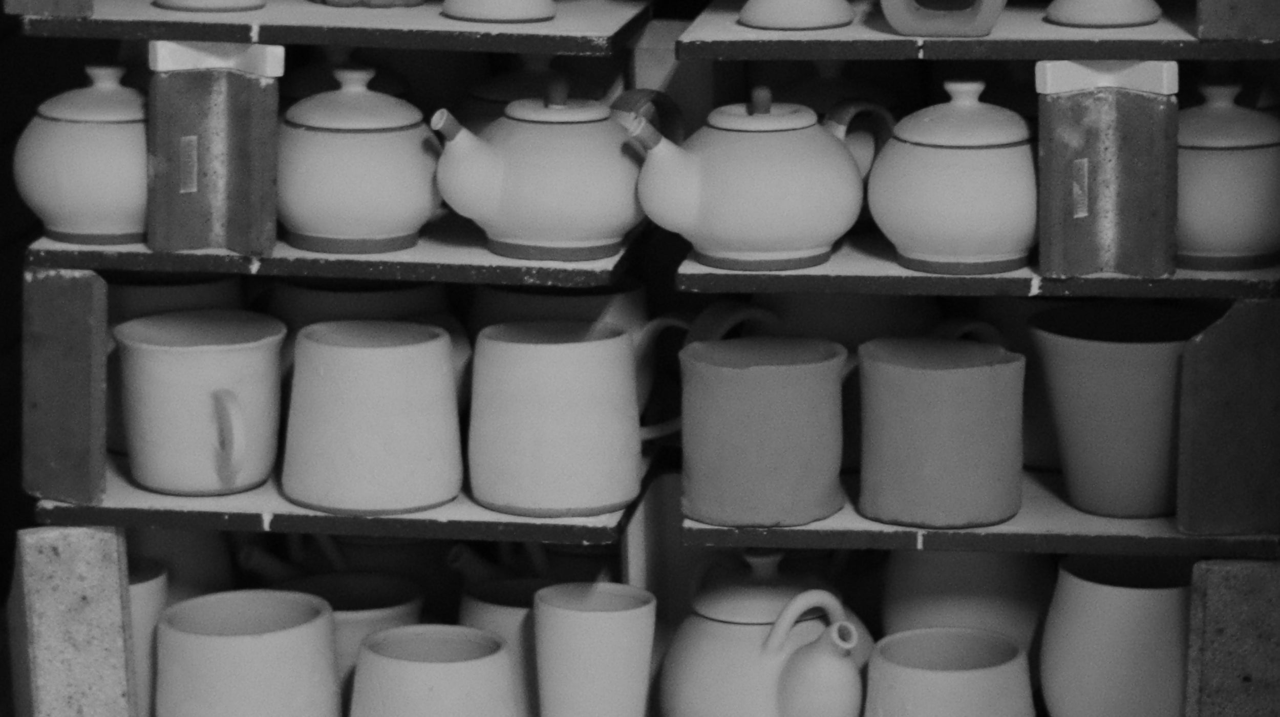 Shelves filled with various Japanese ceramic pots and teapots in a black and white photo, Tsukushi